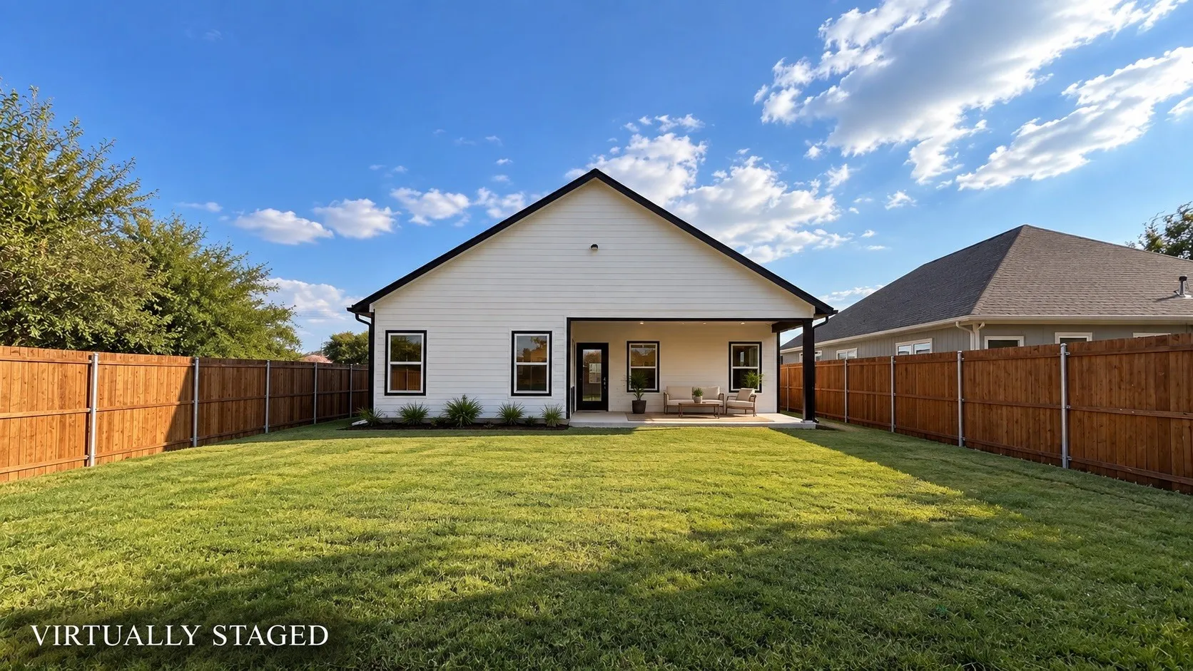 Expansive backyard featuring a manicured lawn, full privacy fencing, and a covered concrete patio