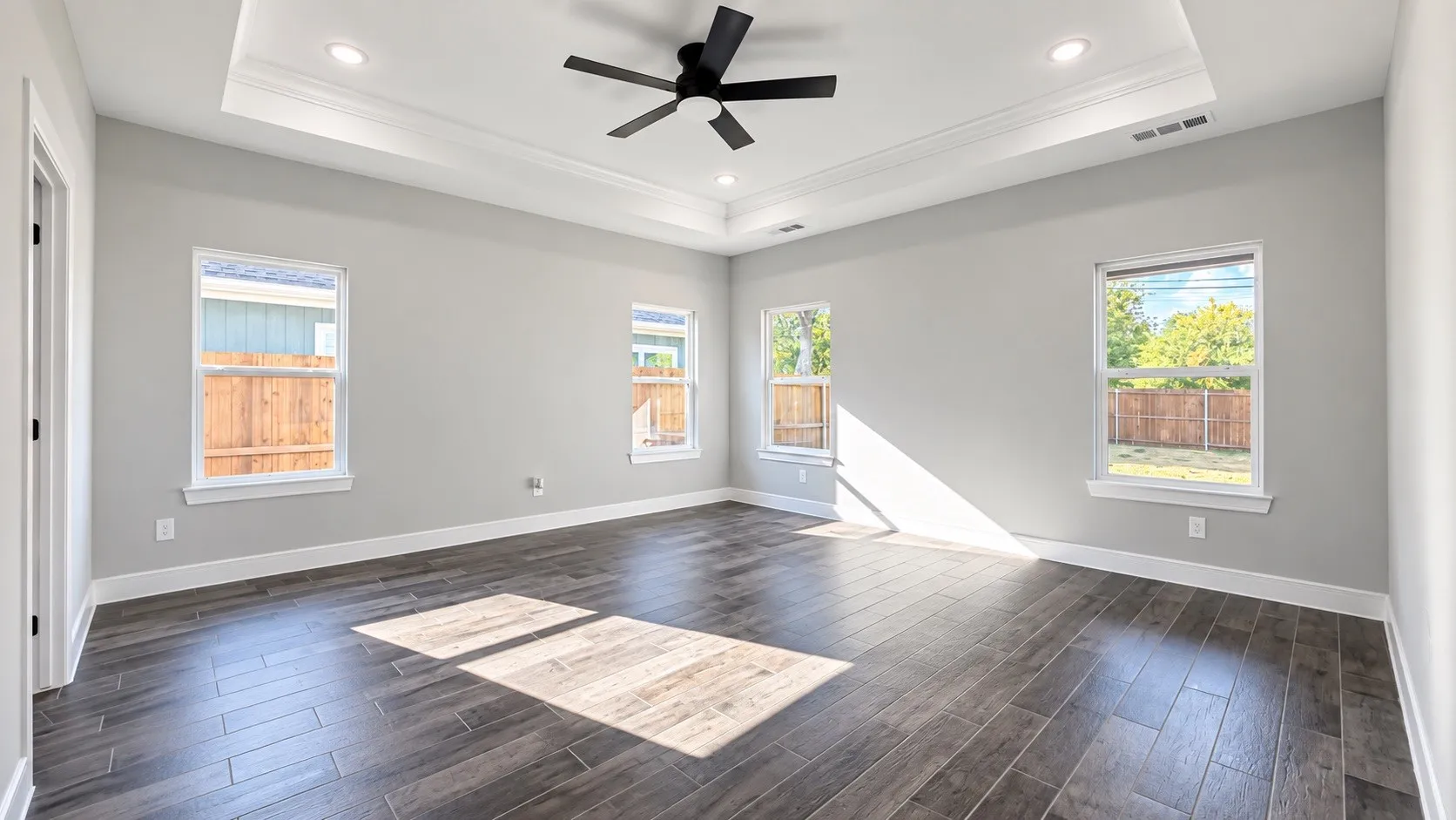 Tray ceiling with recessed lighting and ceiling fan, wood-finish flooring, and multiple windows