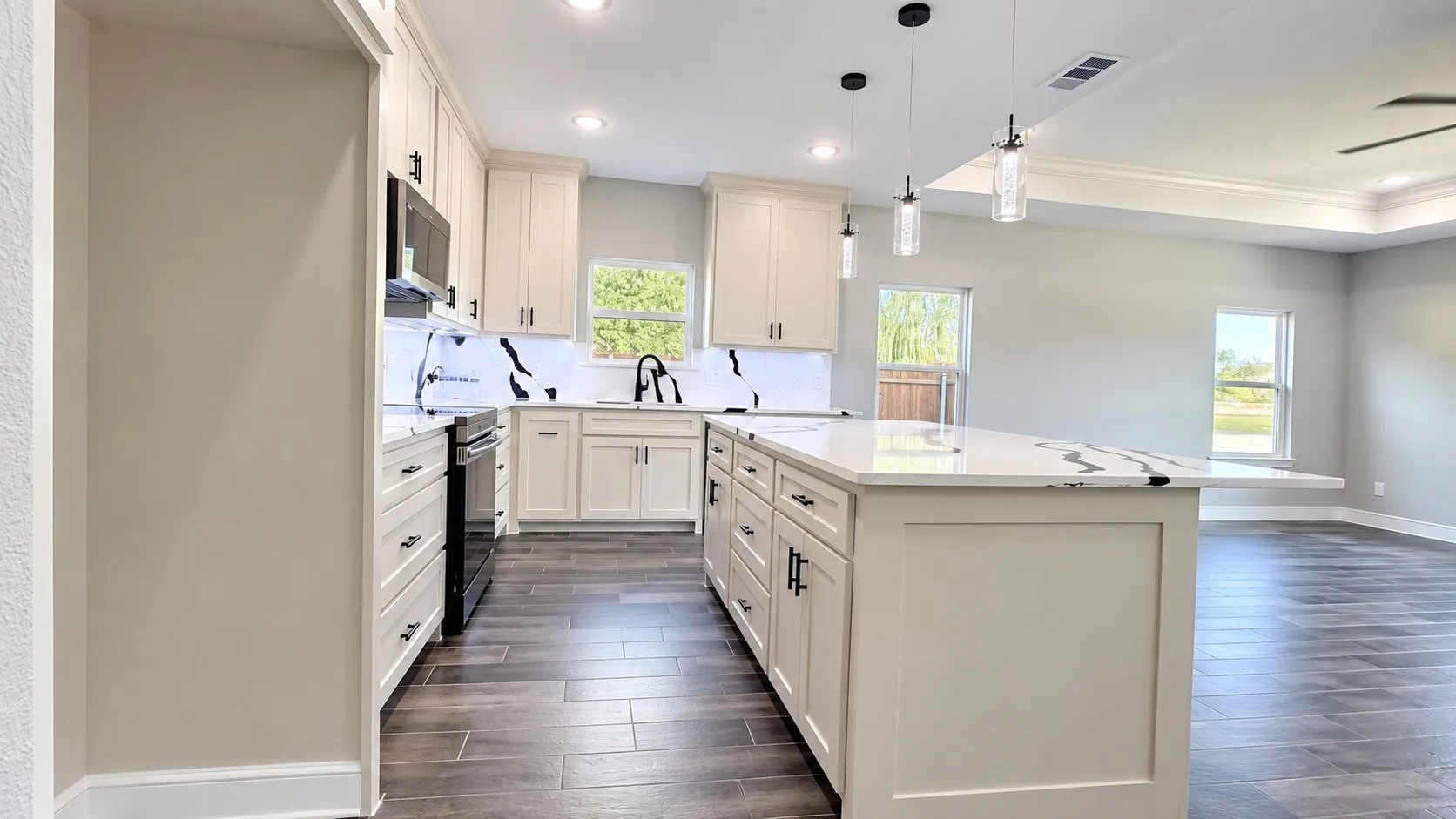 Kitchen featuring an expansive island with a white countertop, cream cabinetry, a black faucet, and wood-look flooring