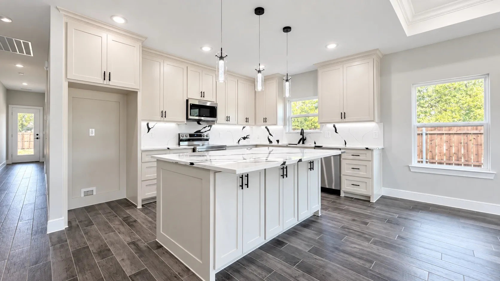 Modern kitchen featuring a central island, light-toned cabinetry, stainless steel appliances, and wood-finish flooring