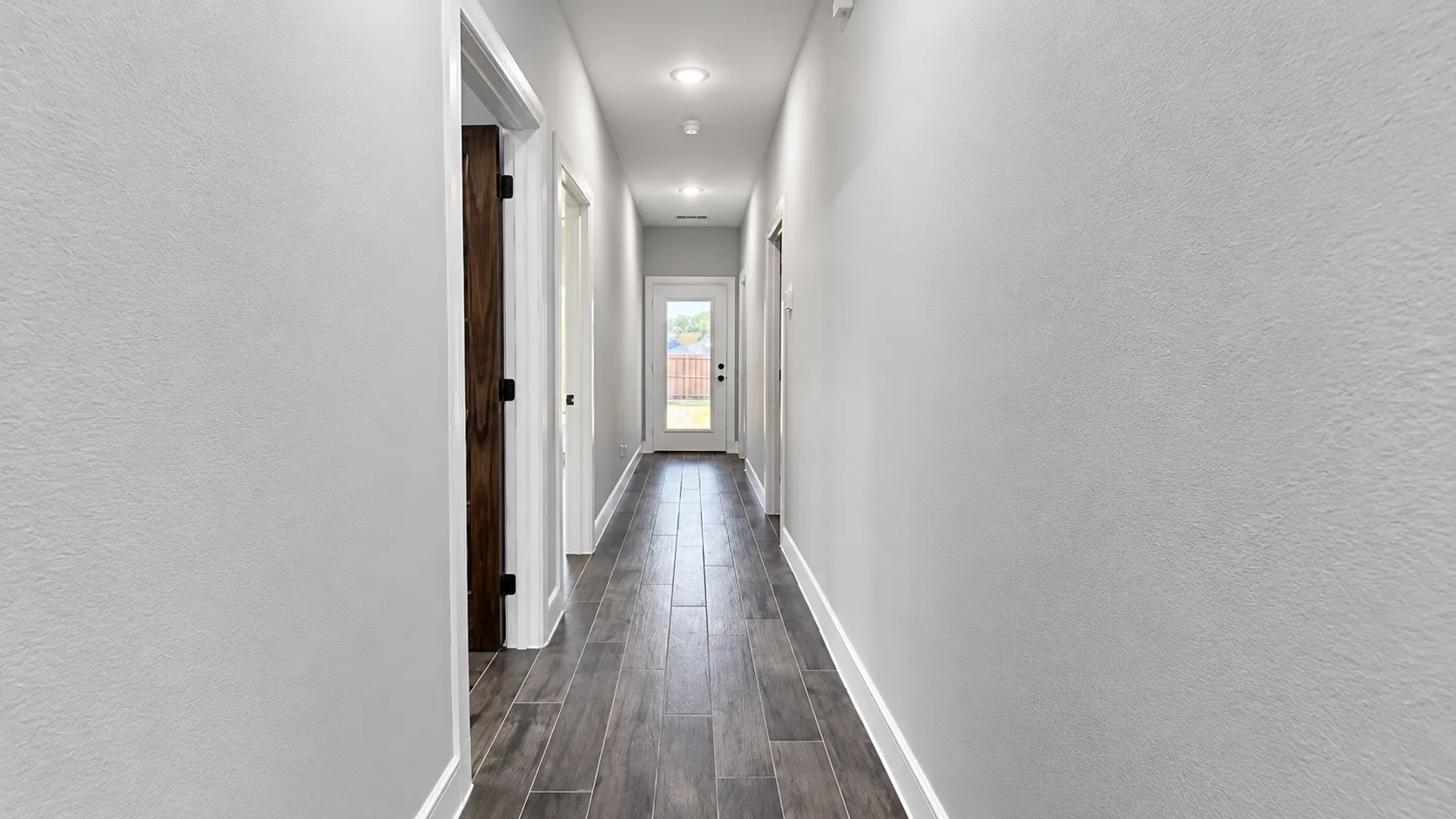 Hallway with wood-finish flooring, recessed lighting, and a rear exterior door with a glass panel