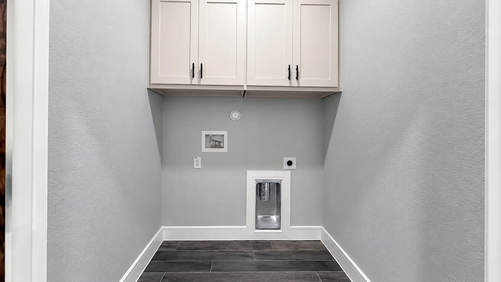 Overhead cabinetry with matte black hardware, utility hookups, and wood-look flooring