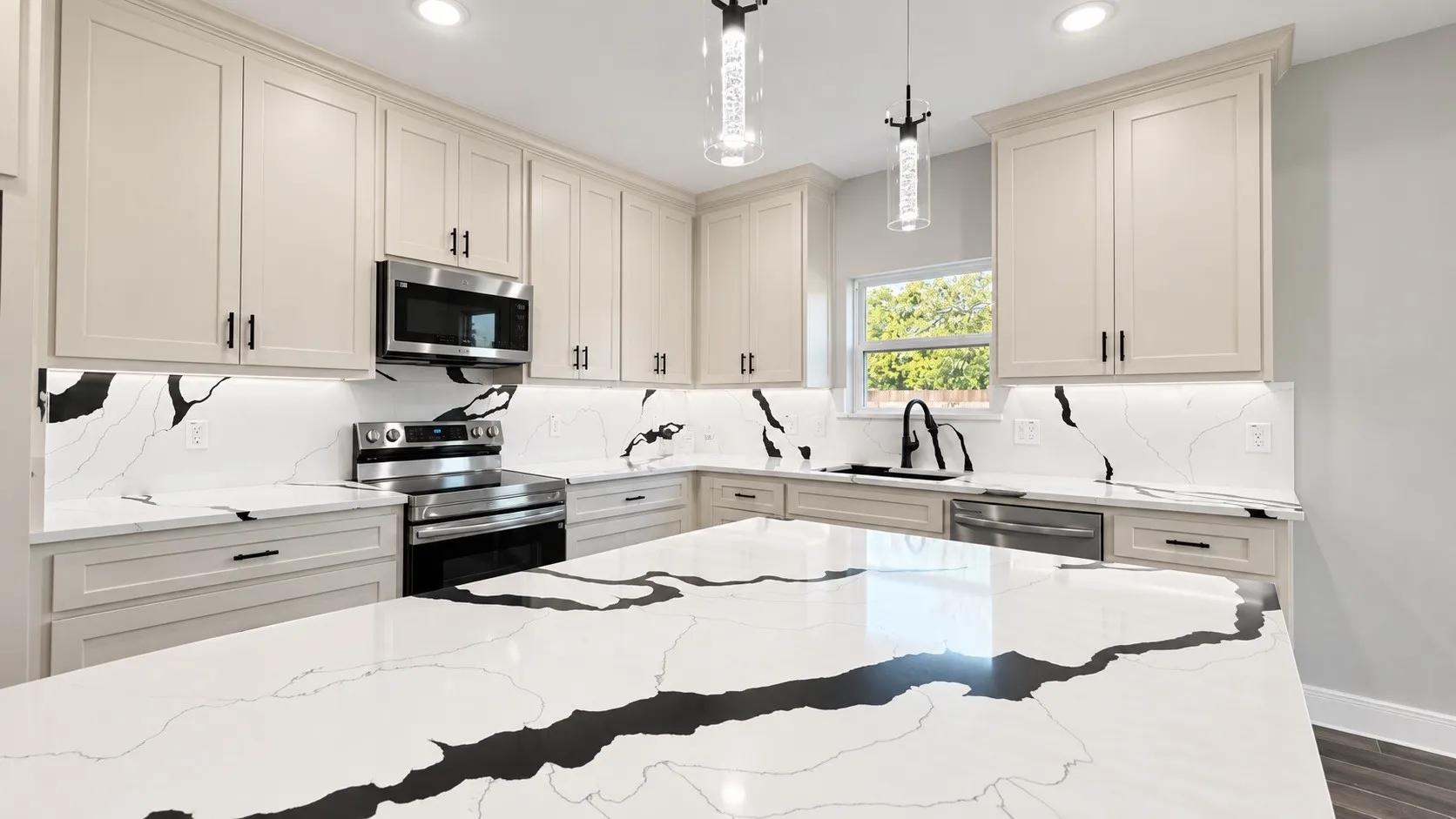 Expansive kitchen island with a waterfall edge, complemented by white cabinetry and stainless steel appliances