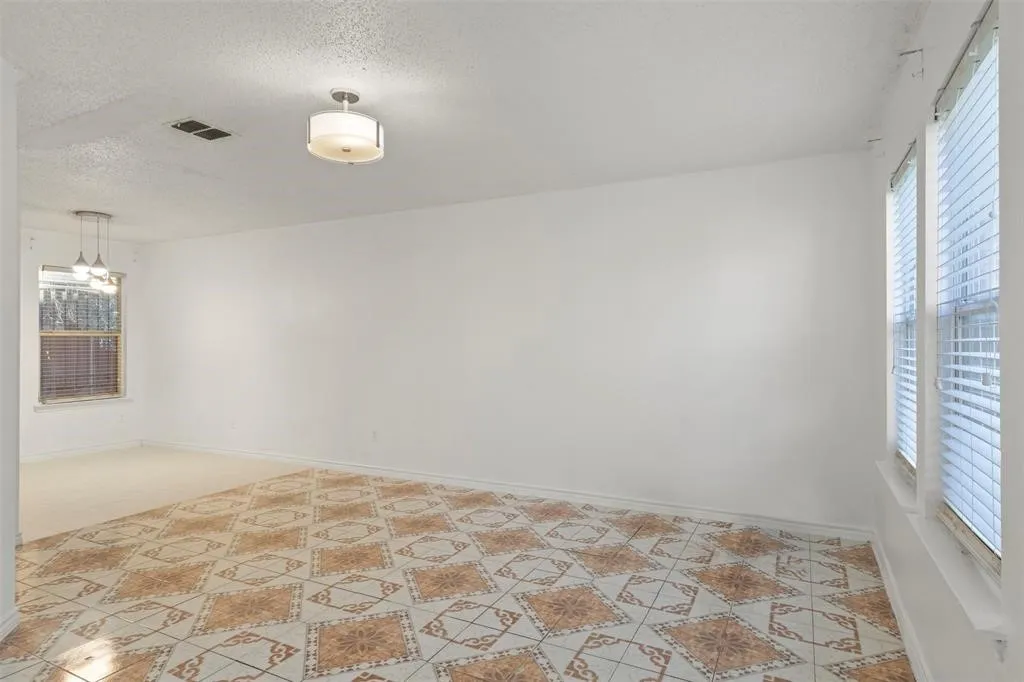 Patterned tile flooring, multiple windows, ceiling-mounted light fixture, and pendant lighting