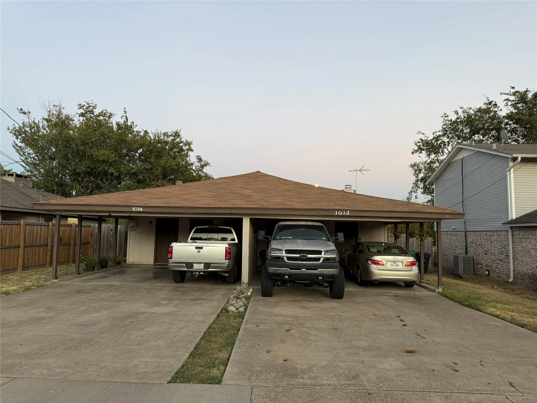 Duplex property featuring a hip roof, two dedicated carport spaces, and a concrete driveway