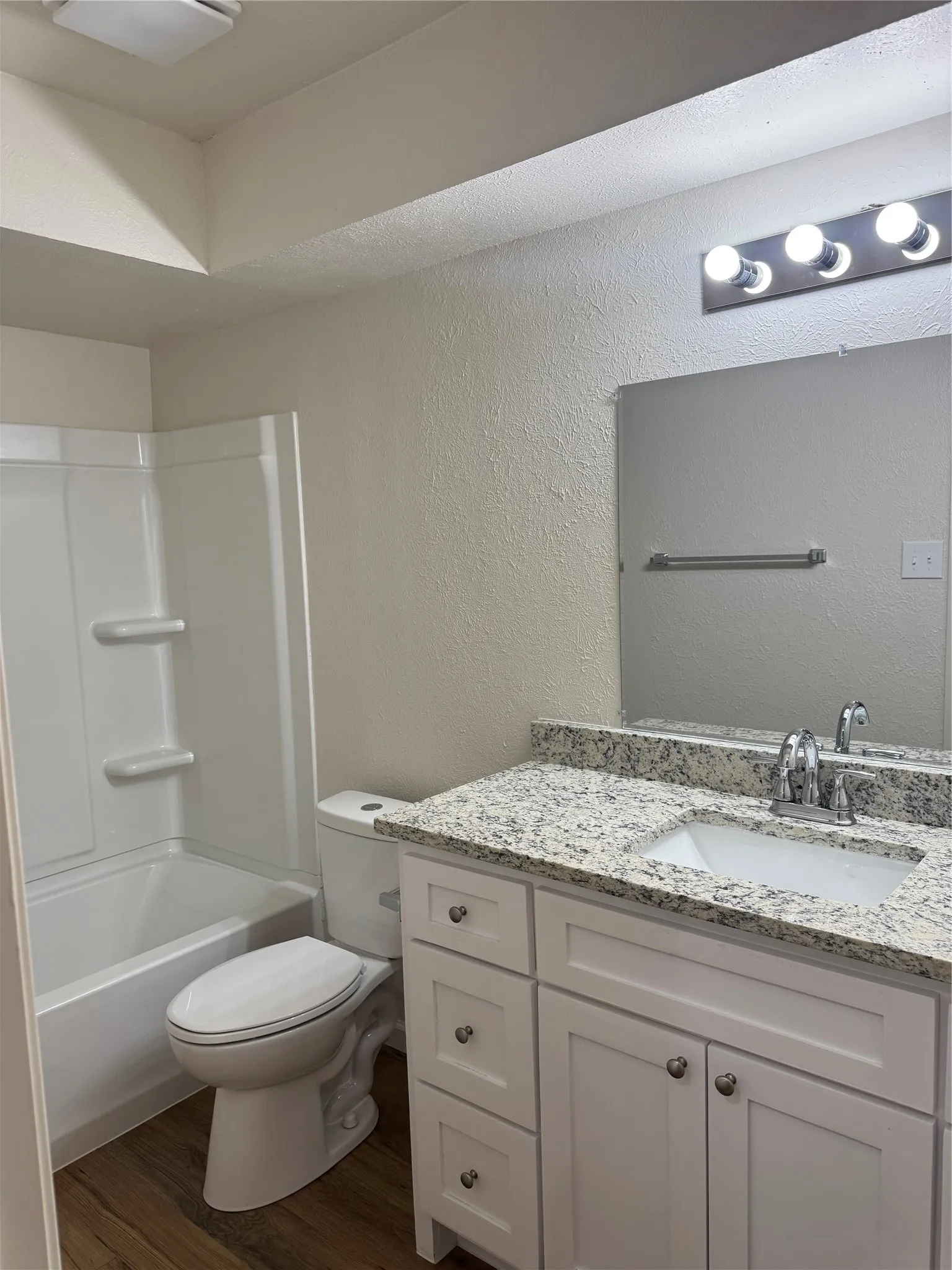 White vanity with brushed nickel hardware, integrated sink, and a speckled countertop