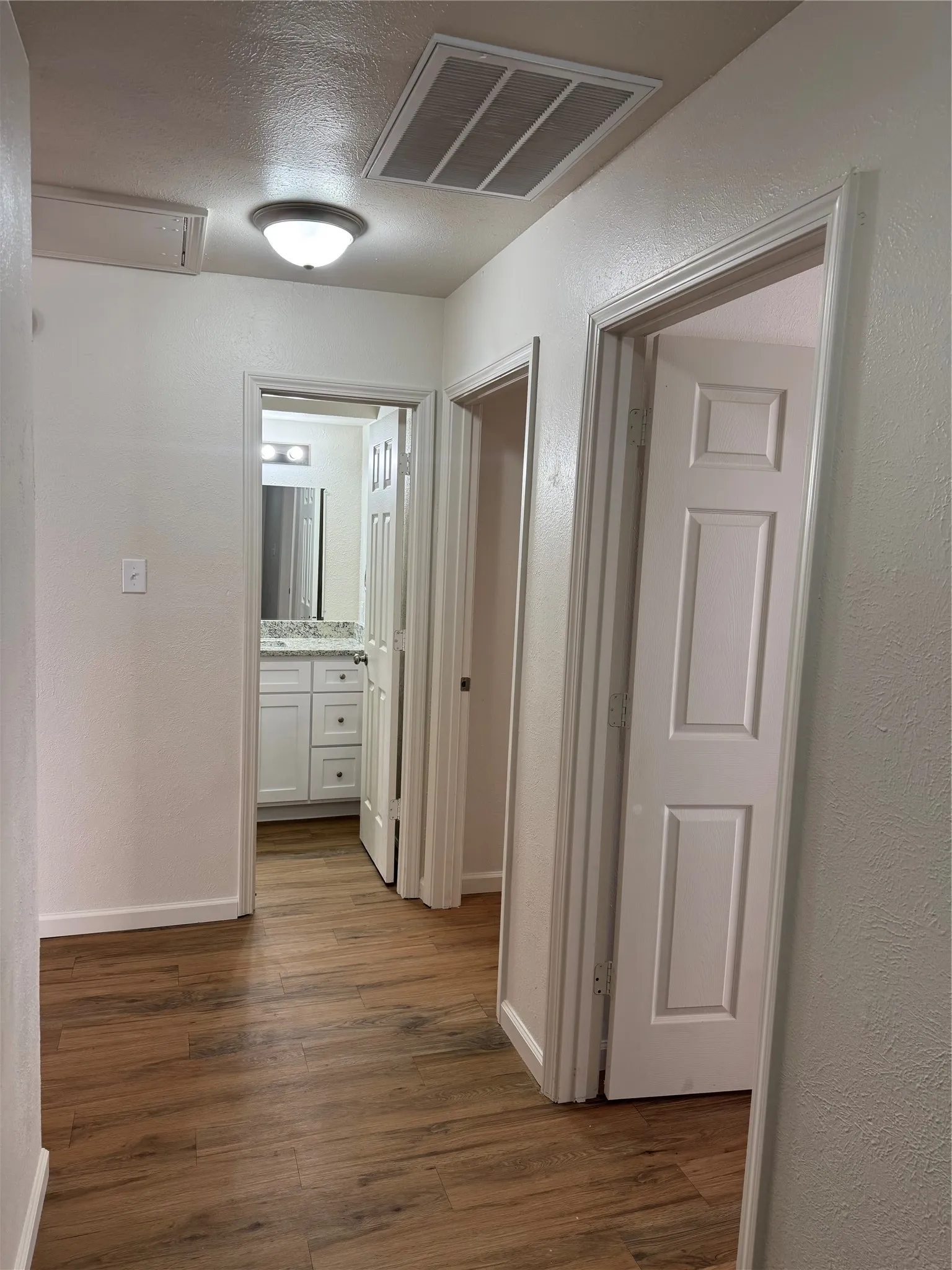 Hallway featuring wood-finish flooring, recessed lighting, and panel doors