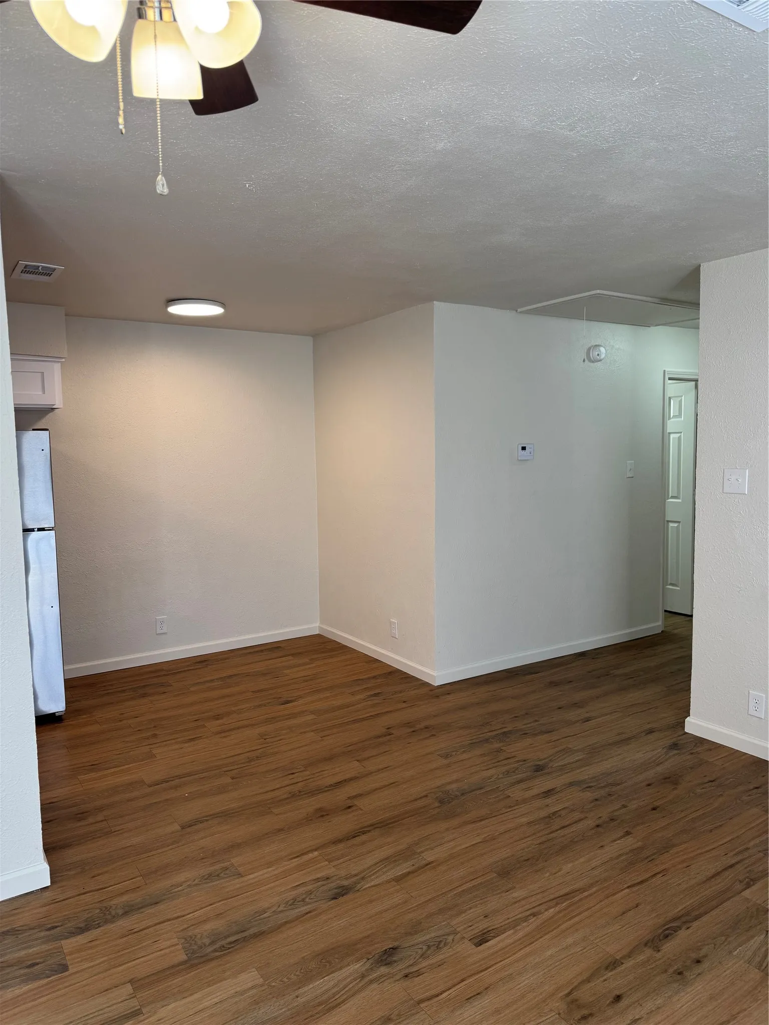 Wood-finish flooring, white walls, ceiling fan, and recessed lighting fixtures