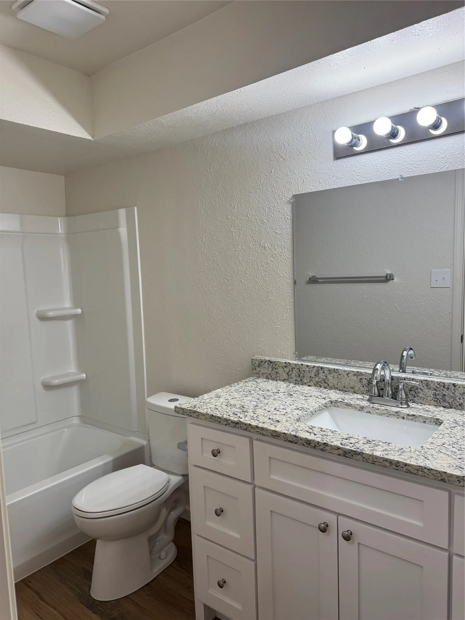 Bathroom featuring a white vanity with cabinetry and drawers, an undermount sink, and a speckled countertop