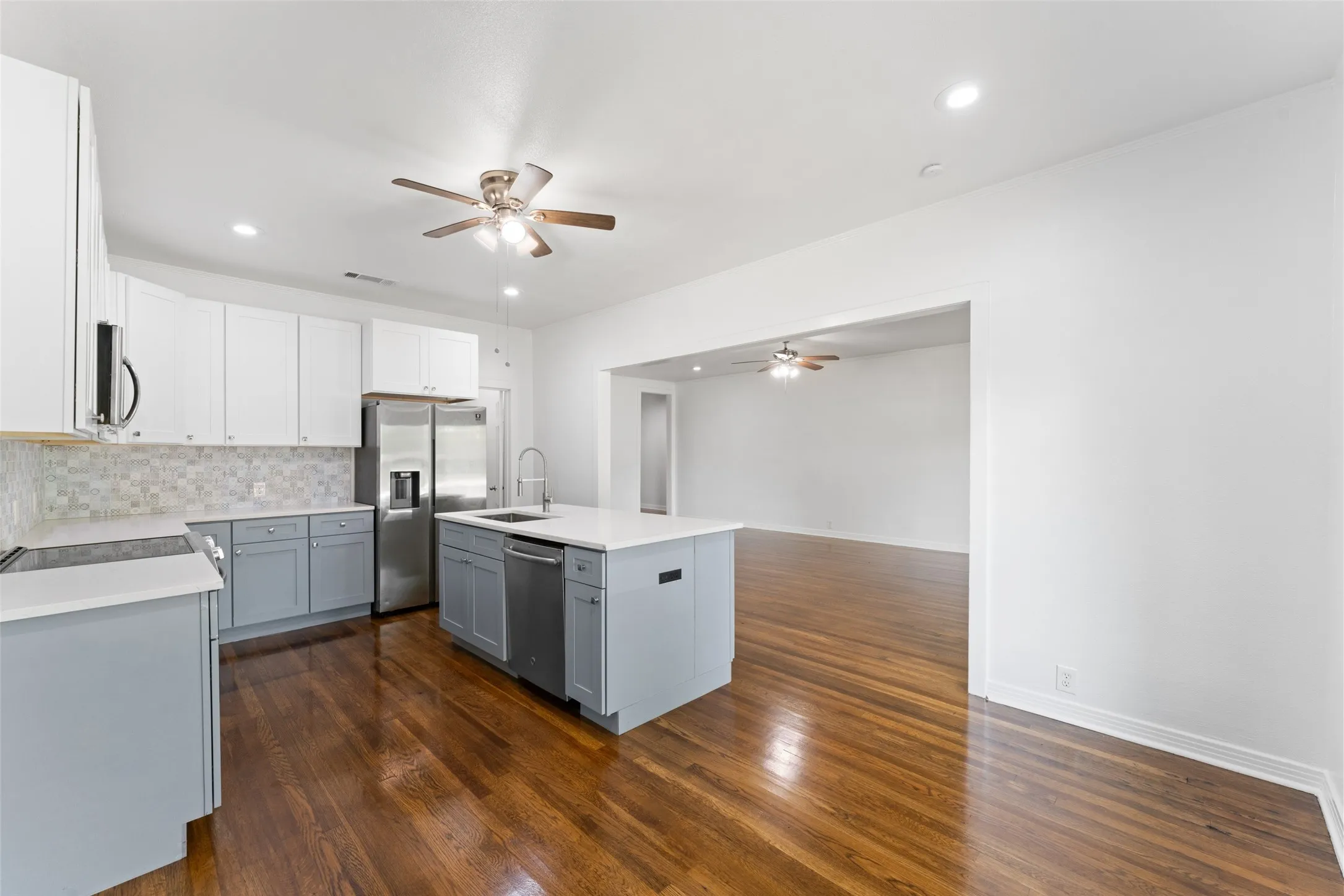 Kitchen featuring two-tone cabinetry, stainless steel appliances, a center island with sink and dishwasher, recessed lighting, and wood-finish flooring
