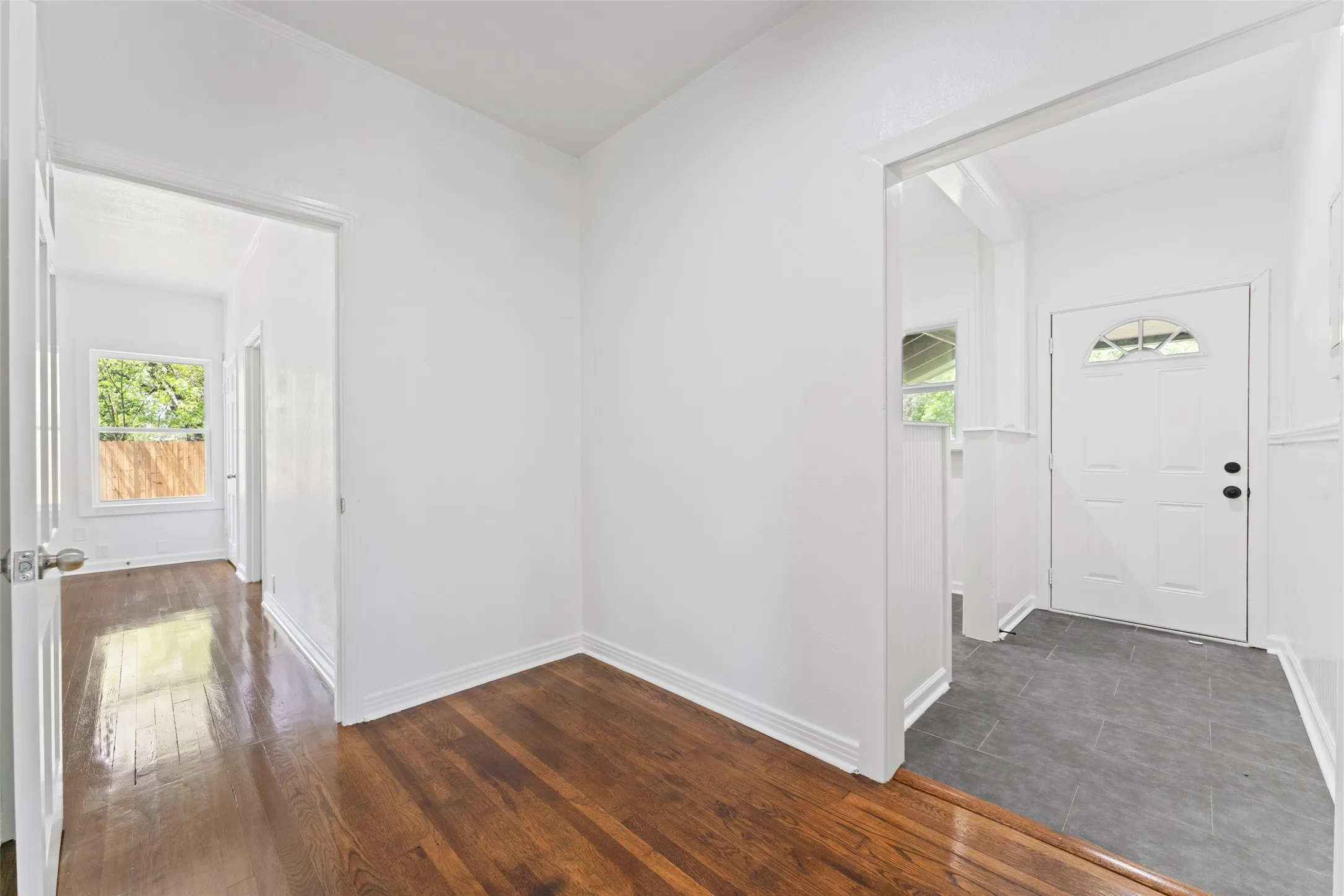 Wood-finish flooring throughout, white interior walls, and tile flooring at entry