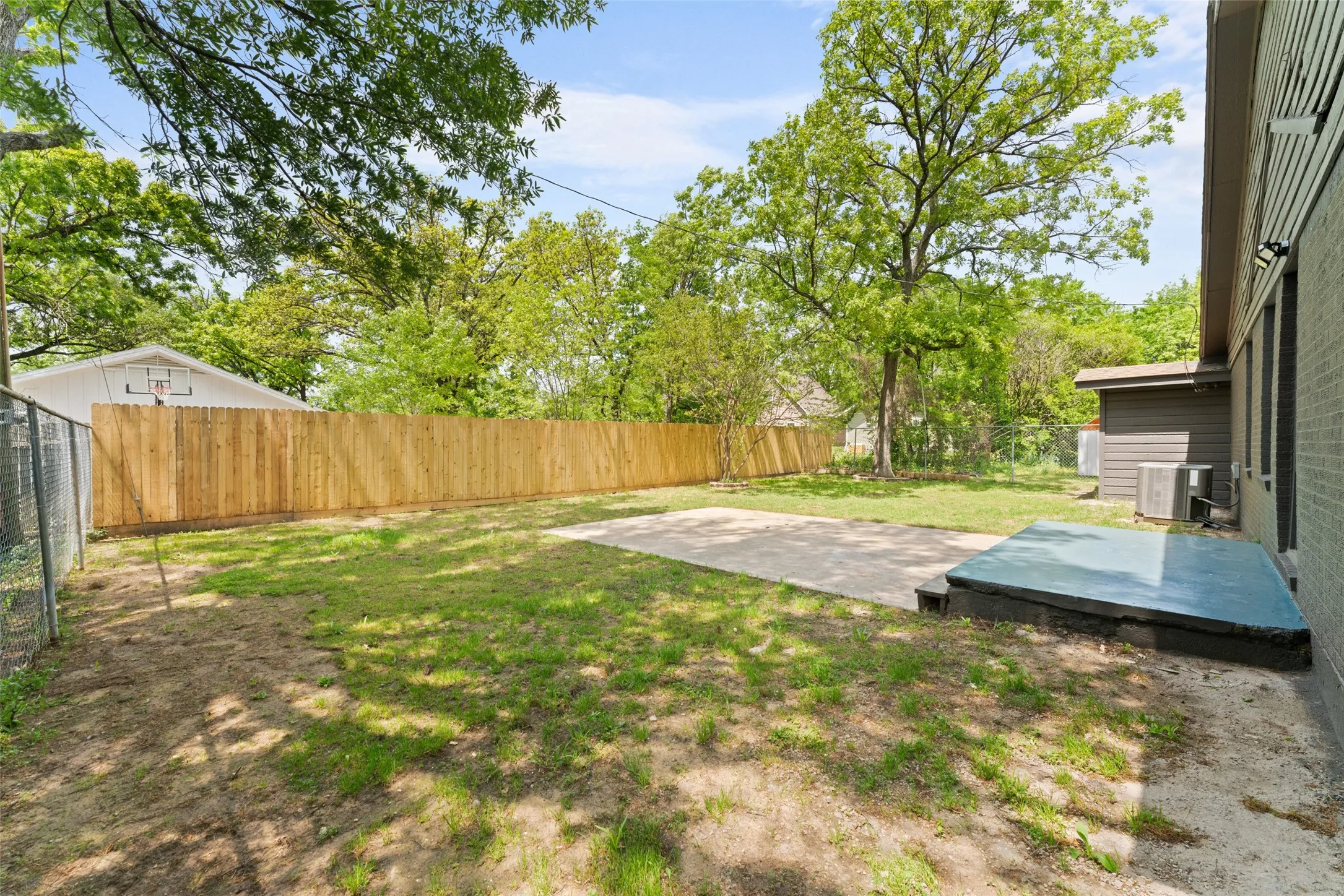 Expansive backyard with a level lawn, concrete patio, and privacy fencing
