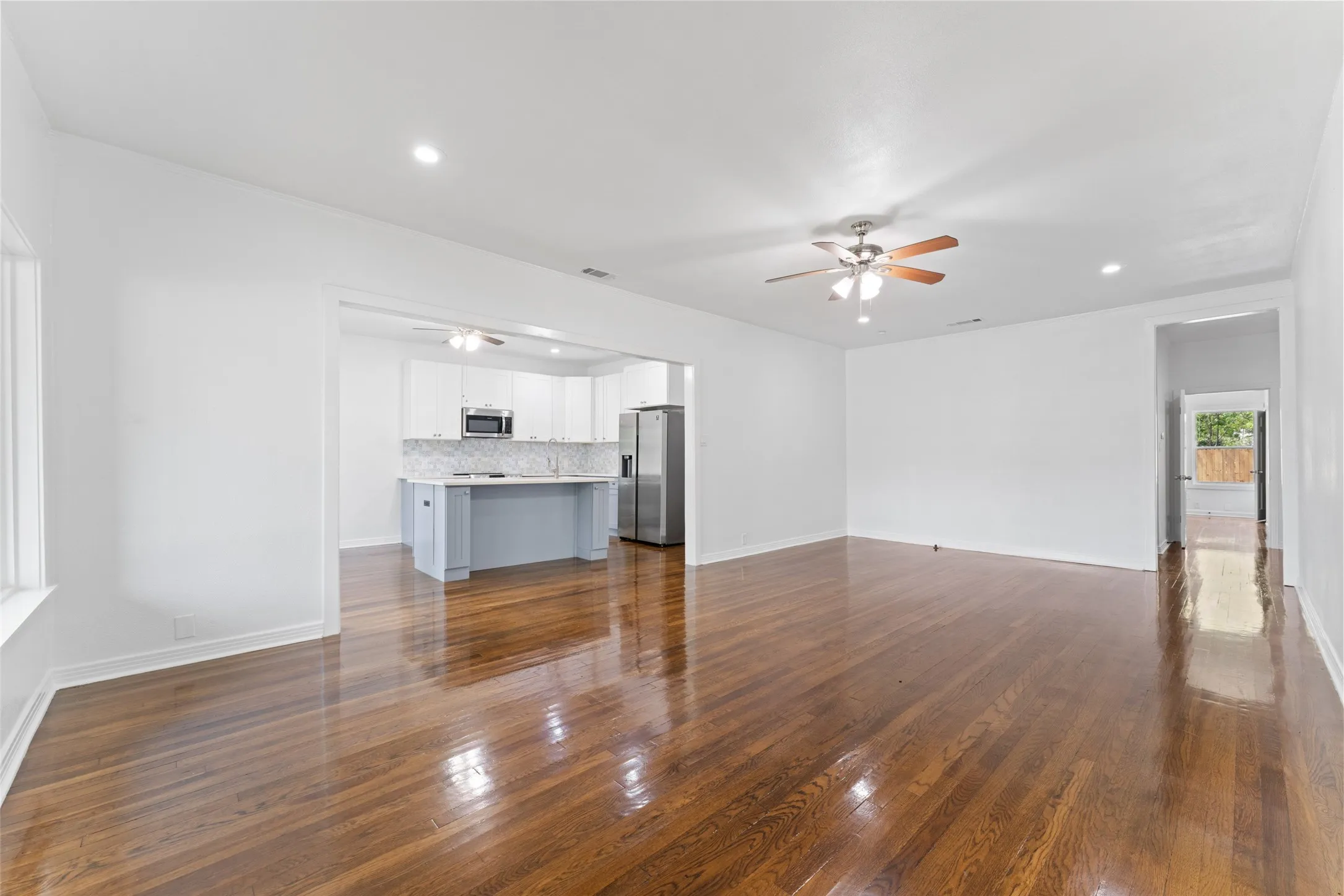 Hardwood flooring throughout, recessed lighting, ceiling fan, white cabinetry, and stainless steel appliances