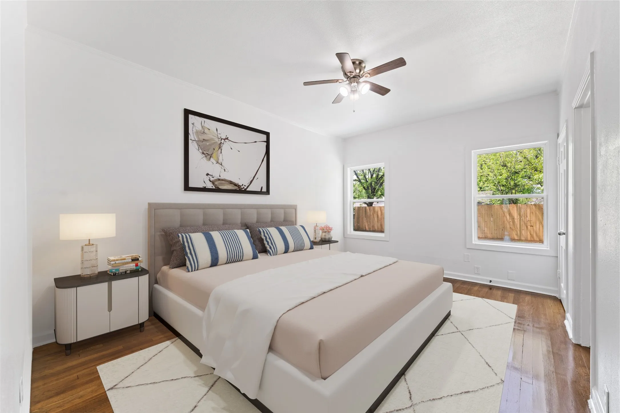 Hardwood flooring, white walls, two windows, and ceiling fan