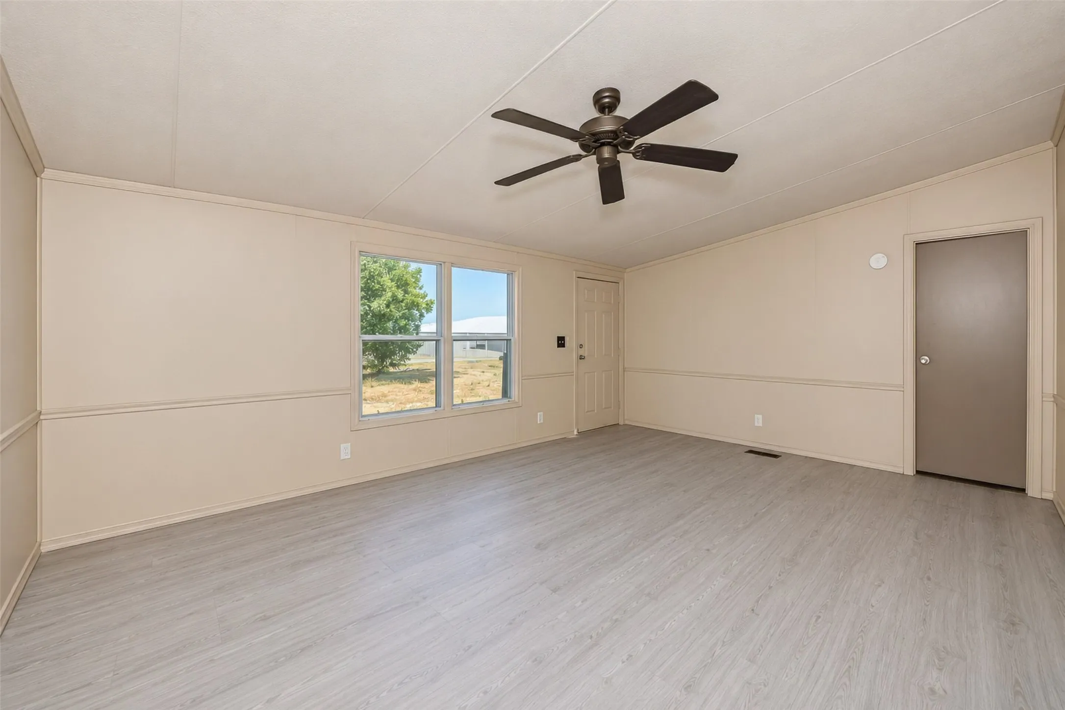 Light-colored wood-finish flooring, neutral wall tones, and a ceiling fan with integrated lighting