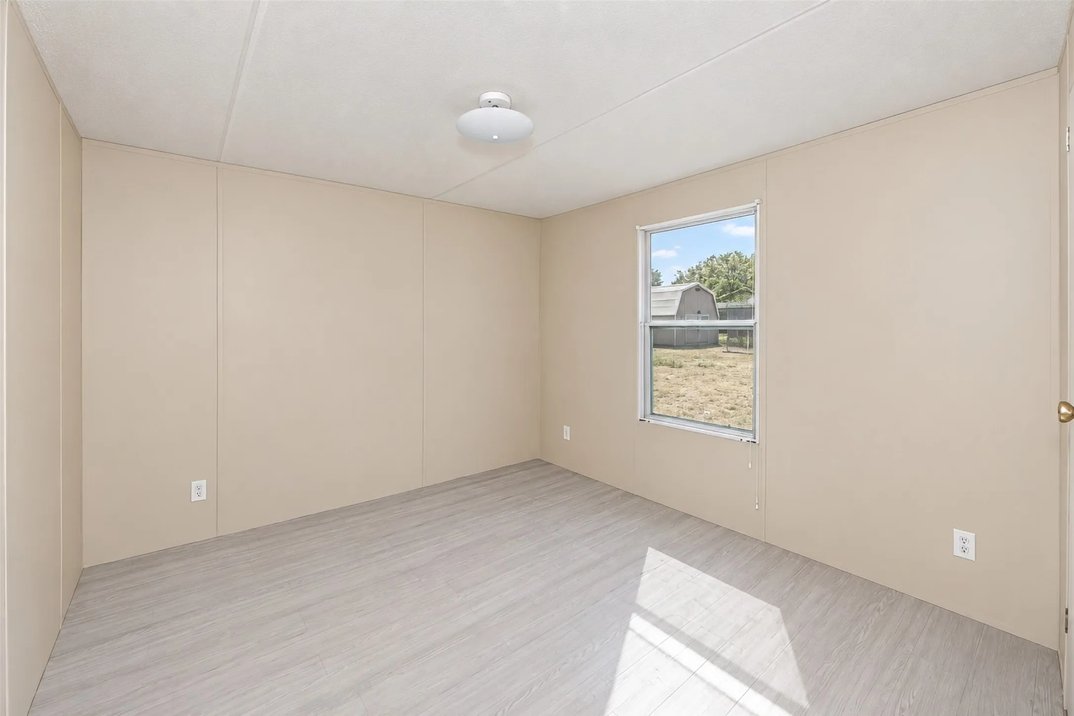 Light wood-finish flooring, neutral wall panels, and a ceiling-mounted light fixture
