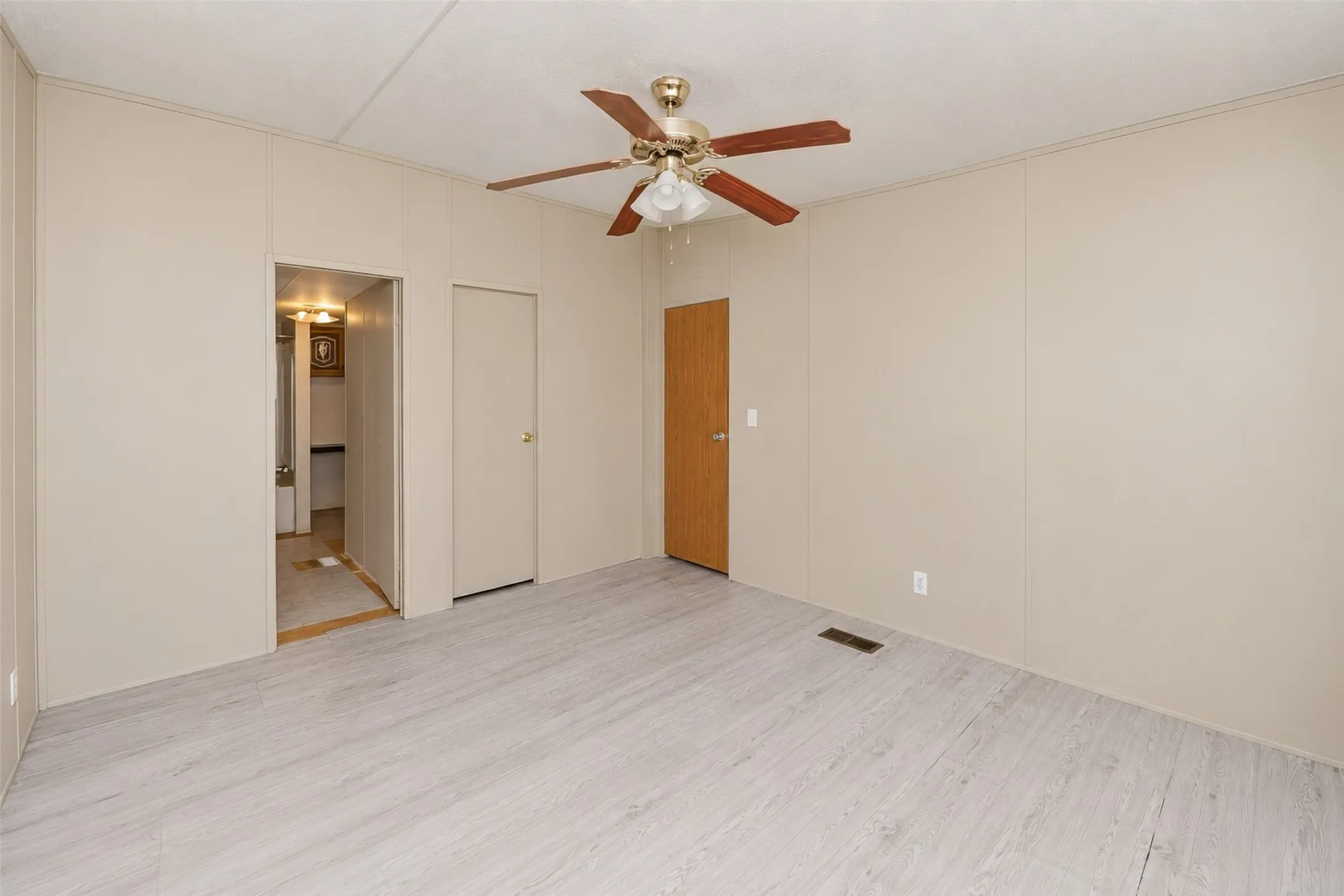 Light wood-finish flooring with a ceiling fan light fixture
