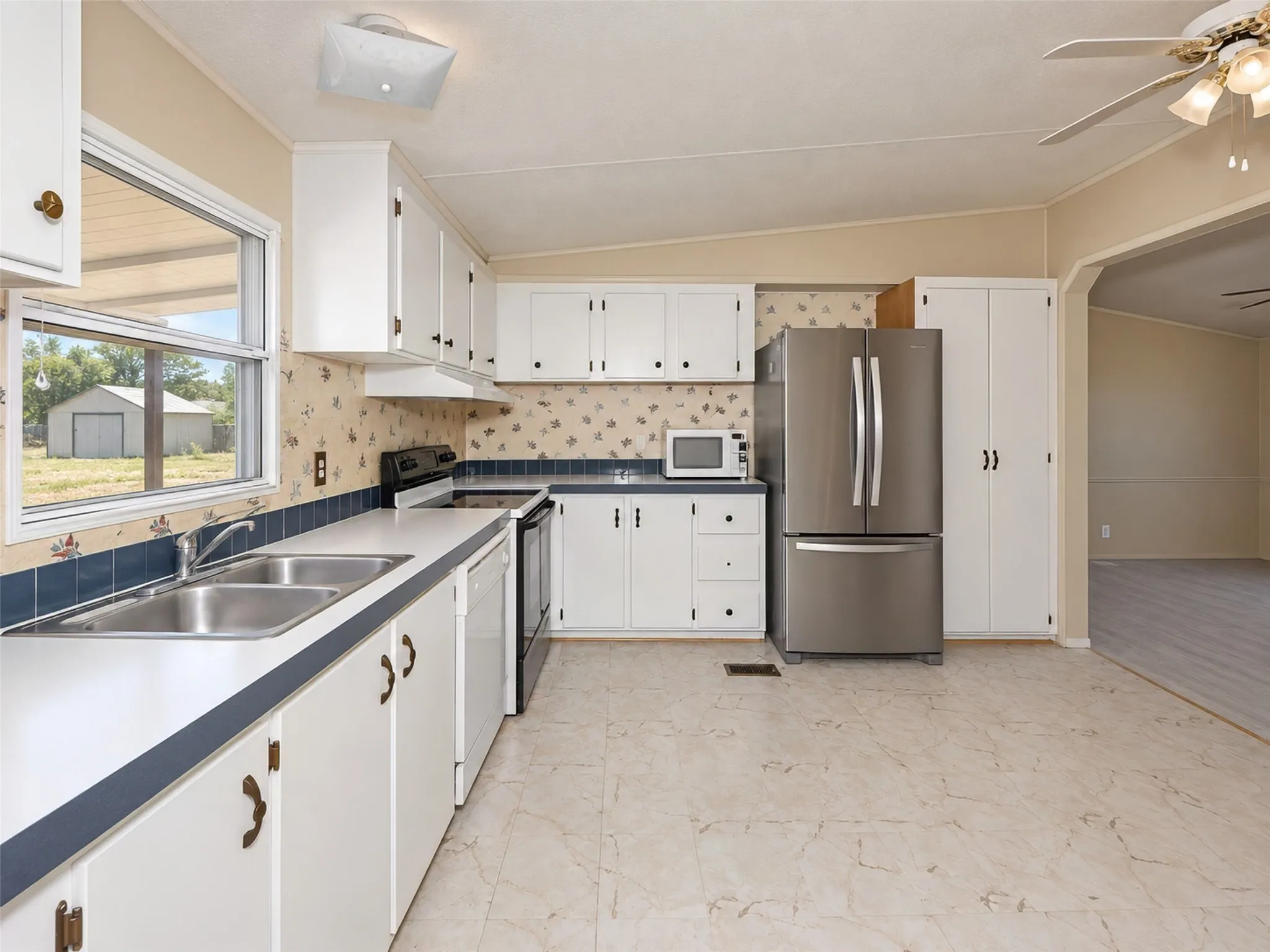 Kitchen featuring white cabinetry, a dual basin stainless steel sink, a stainless steel refrigerator, and tiled flooring