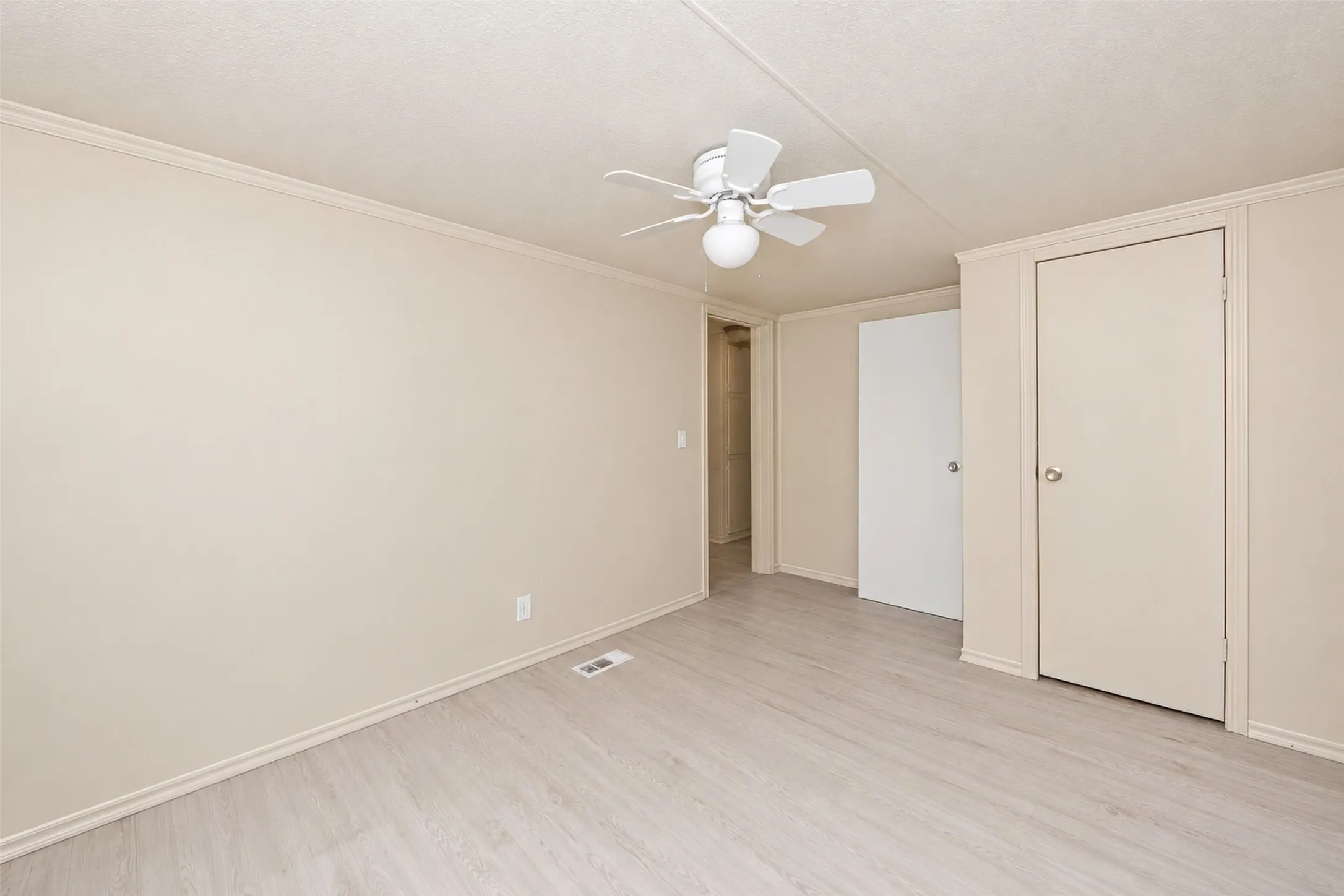 Neutral wall tones, wood-finish flooring, and a ceiling fan