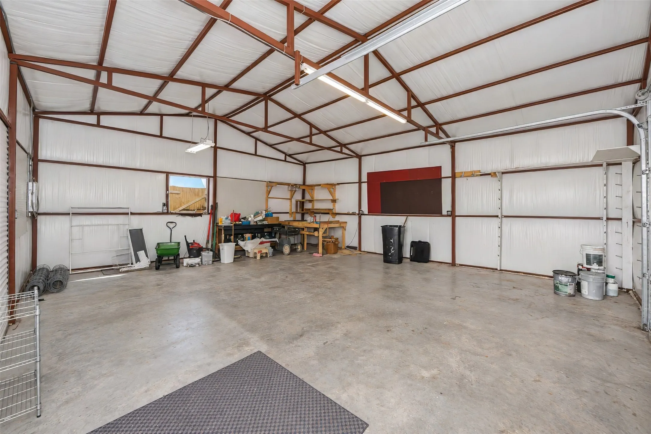 Expansive open-span structure with a concrete floor, metal beam framework, and bright interior lighting