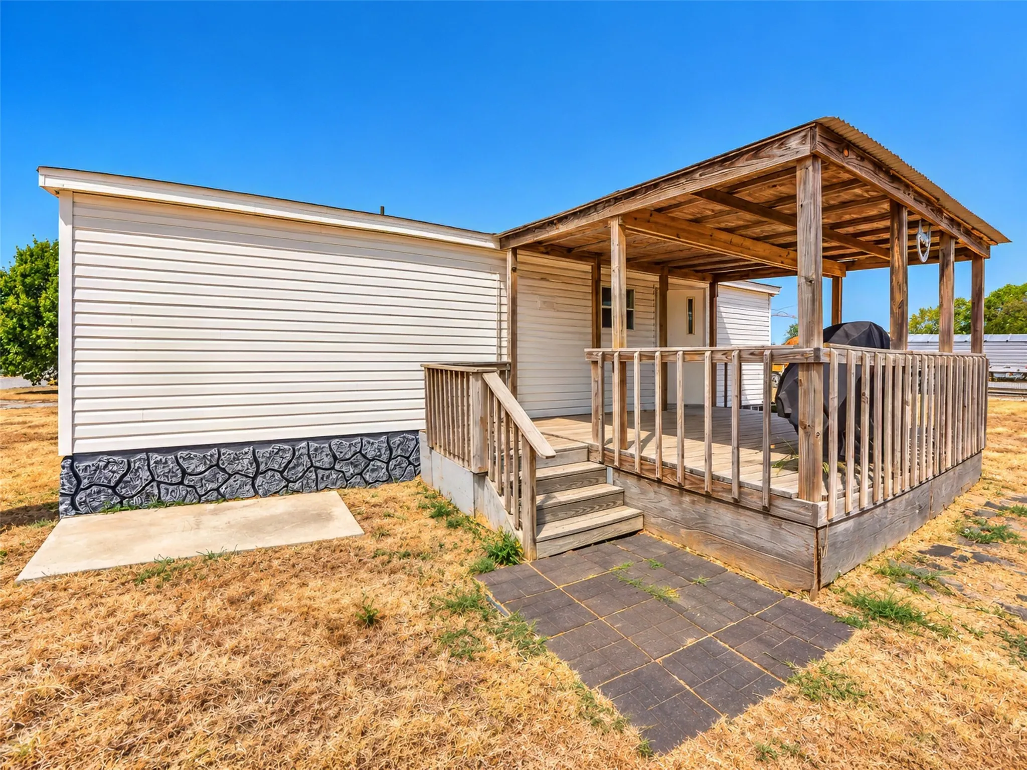 Exterior featuring light-colored siding, a covered wood deck, and a wood-frame railing
