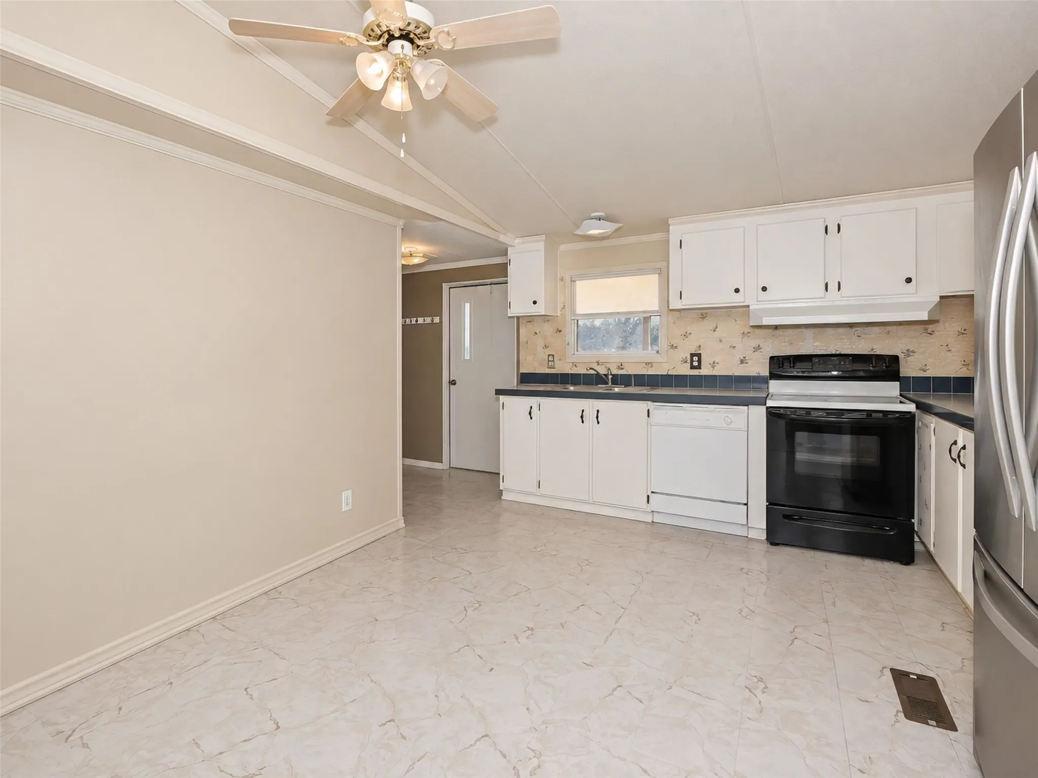 Kitchen featuring white cabinetry, a stainless steel refrigerator, black range, and light-toned tile flooring