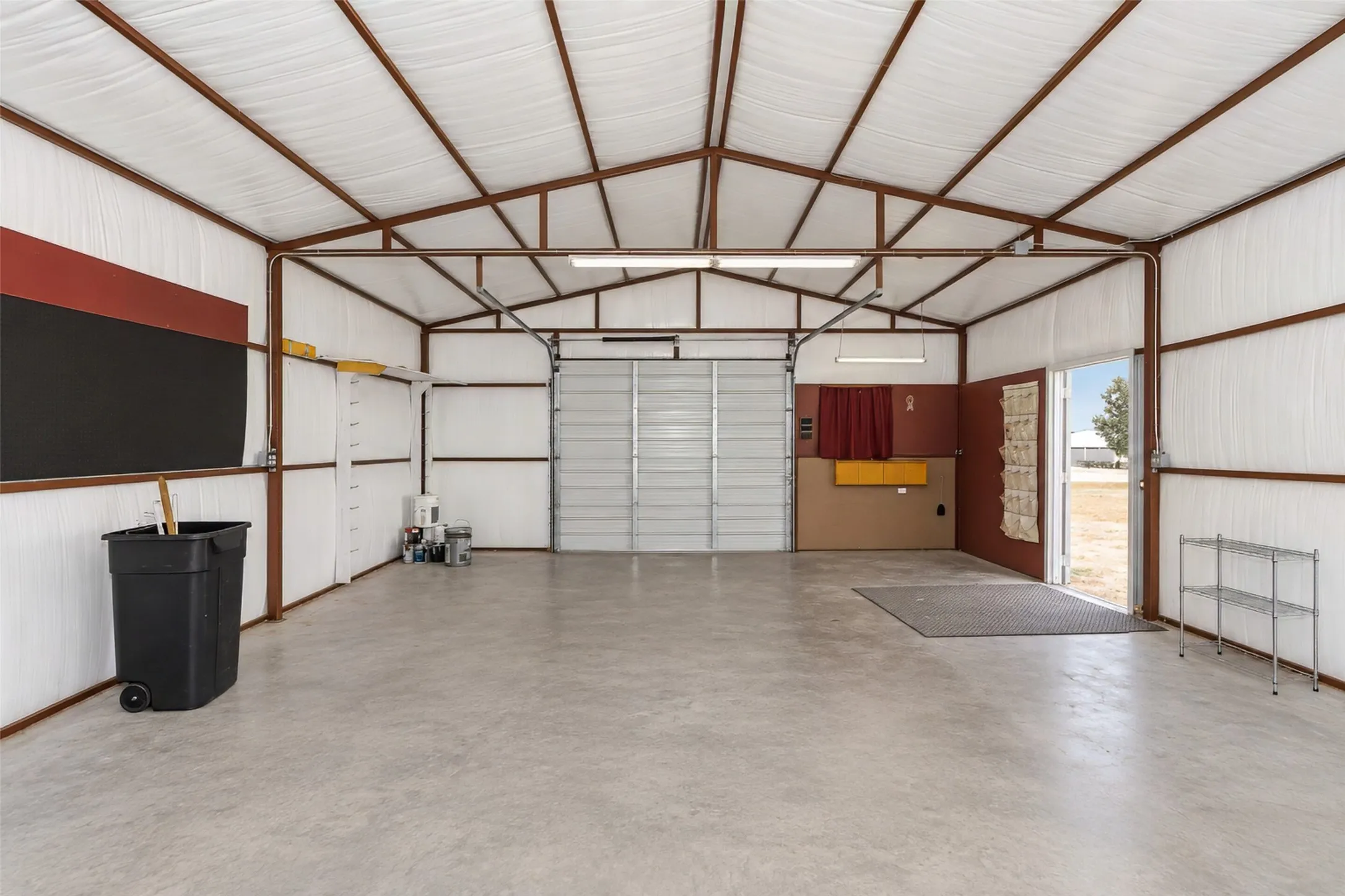 Spacious interior with exposed metal framing, concrete flooring, and an overhead garage door