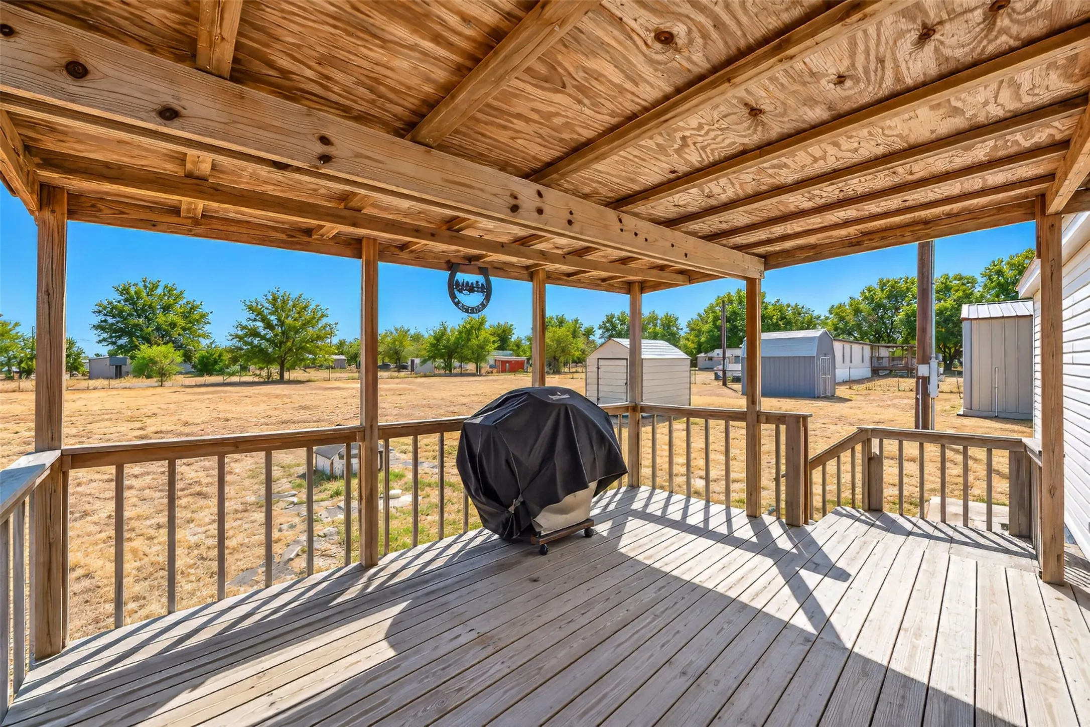 Covered wood deck with wood-finish railing and exposed beam ceiling