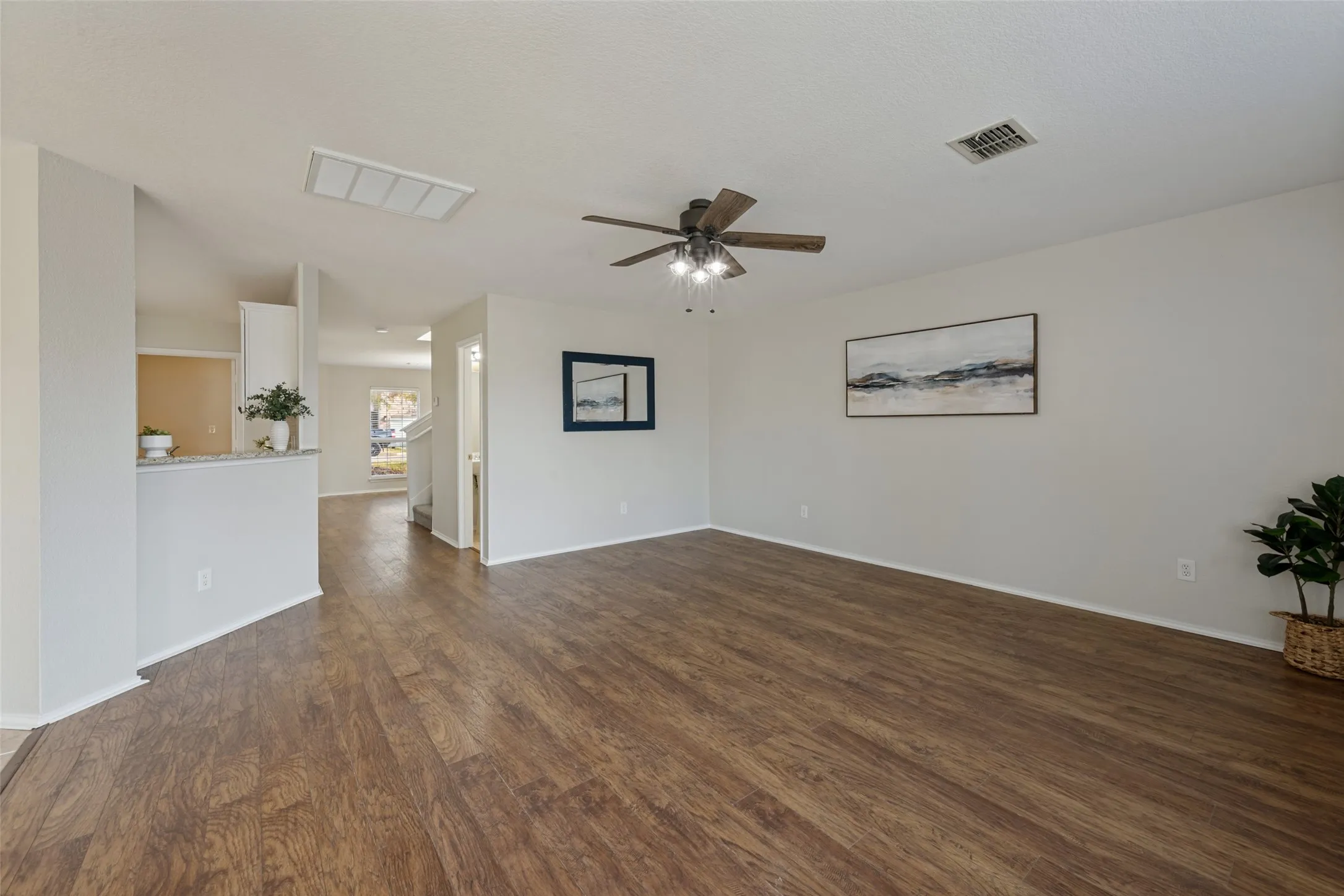 Spacious room with wood-finish flooring, a contemporary ceiling fan with lighting, and light-toned wall paint