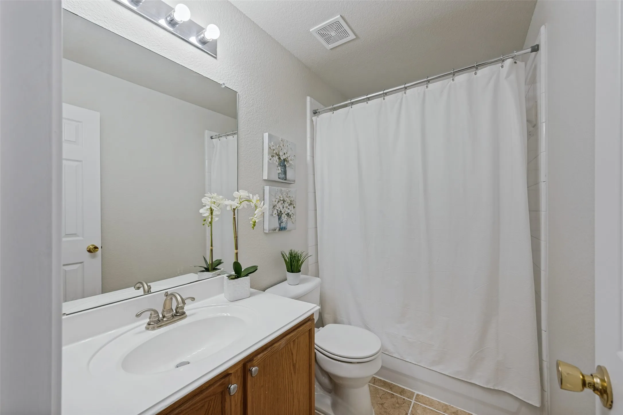 Bathroom featuring a vanity with a wood-finish cabinet, integrated sink, and brushed nickel faucet