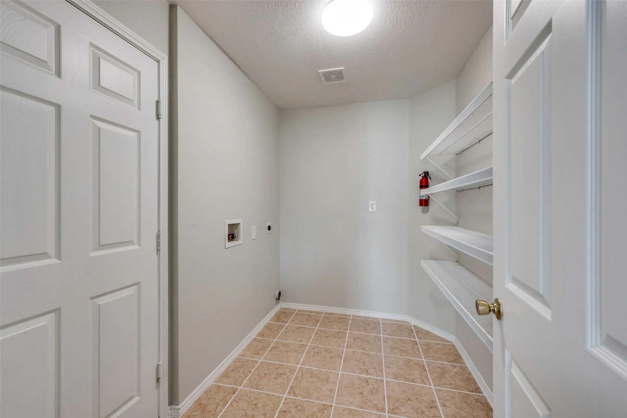Utility room featuring tile flooring, built-in shelving, and a flush mount ceiling light
