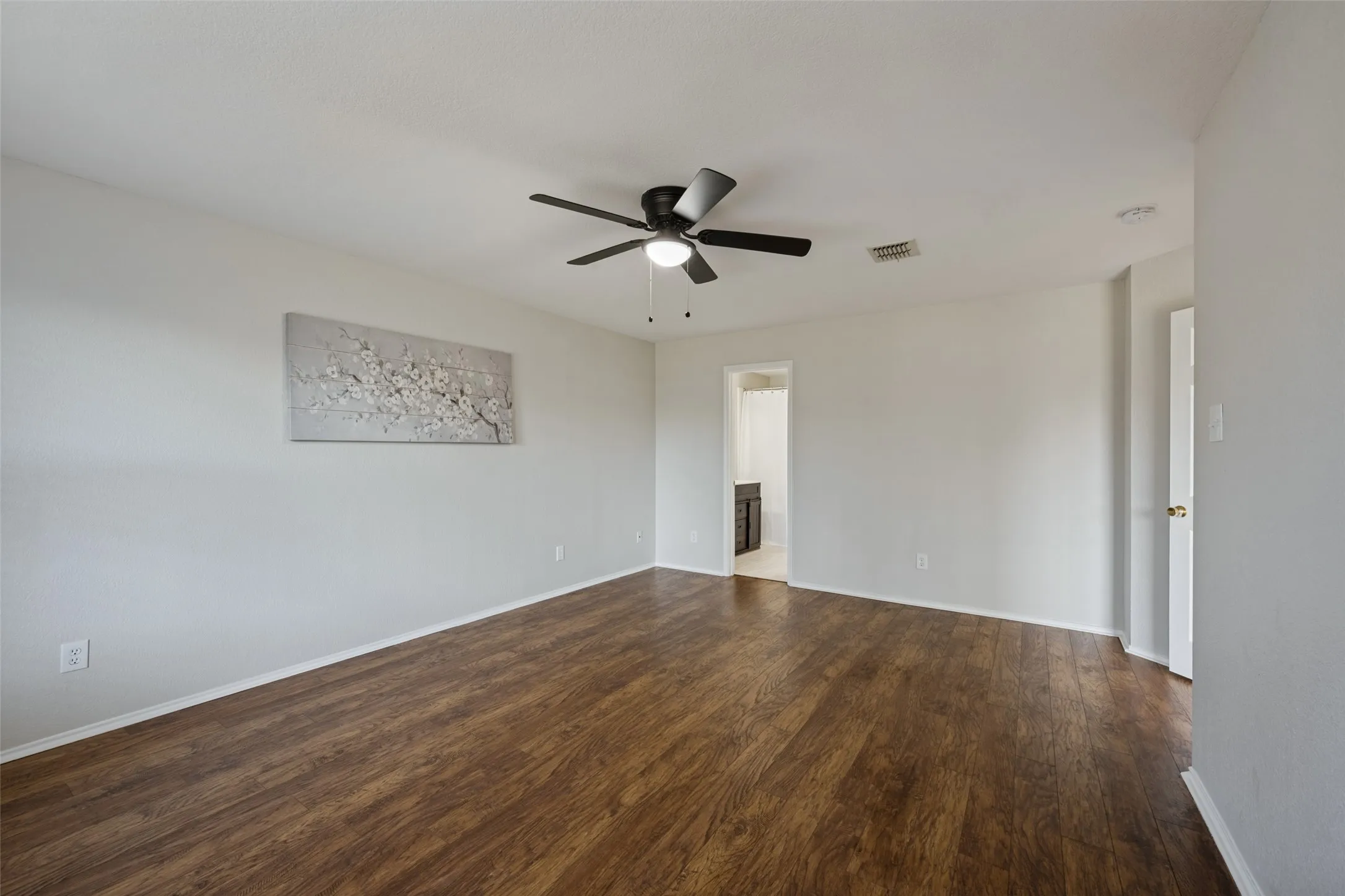 Wood-finish flooring with light-toned walls and a ceiling fan