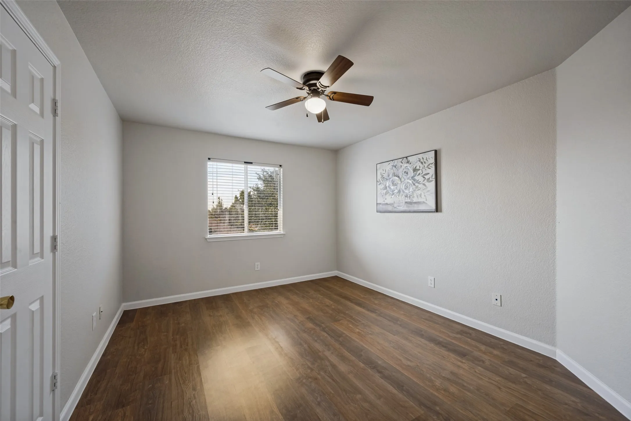 Wood-finish flooring, ceiling fan with light fixture, and window with blinds