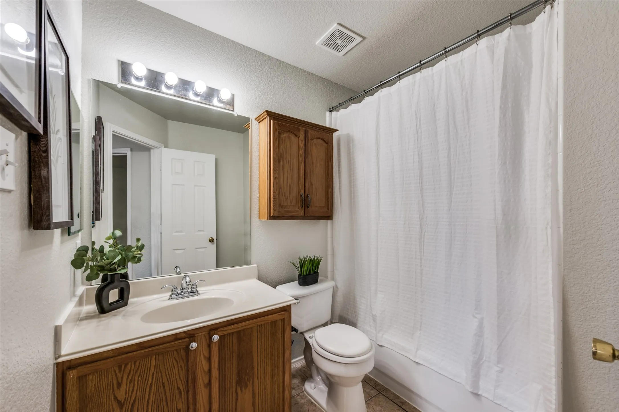 Vanity with a single basin sink, wood-finish cabinetry, and a light-colored countertop