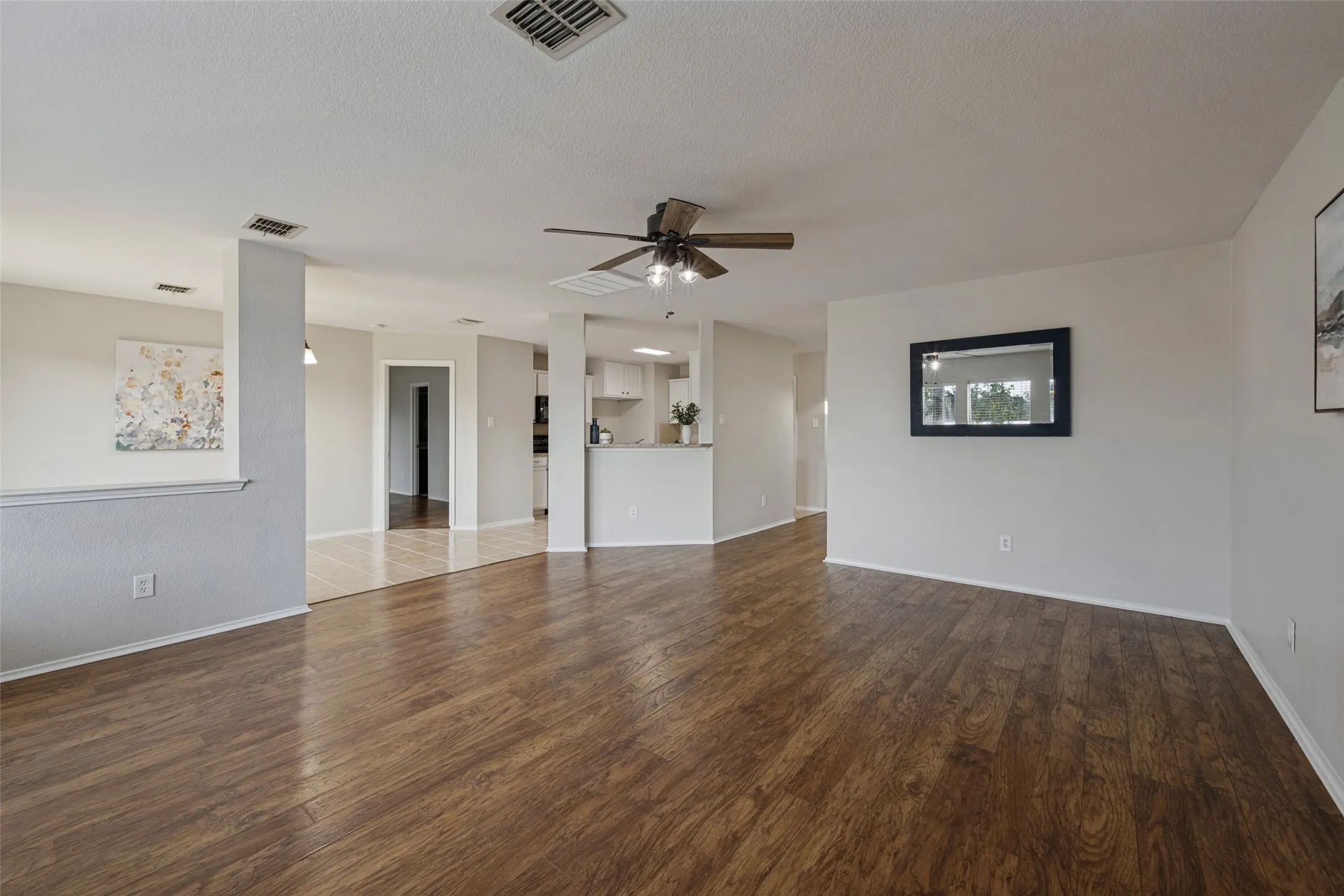 Spacious room featuring wood-finish flooring, light-toned walls, and a ceiling fan