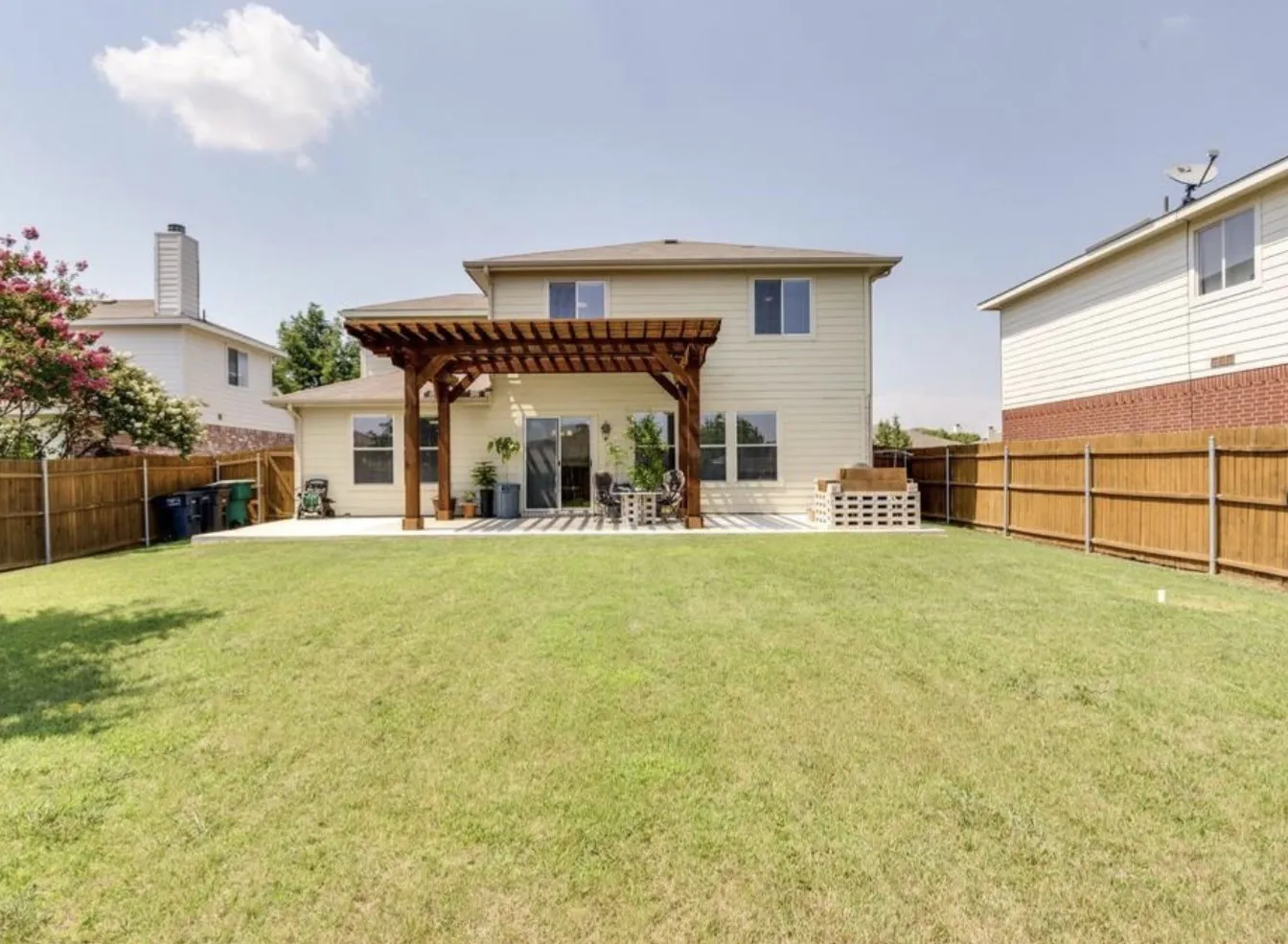 Expansive backyard featuring a concrete patio, a wood pergola, and a privacy fence