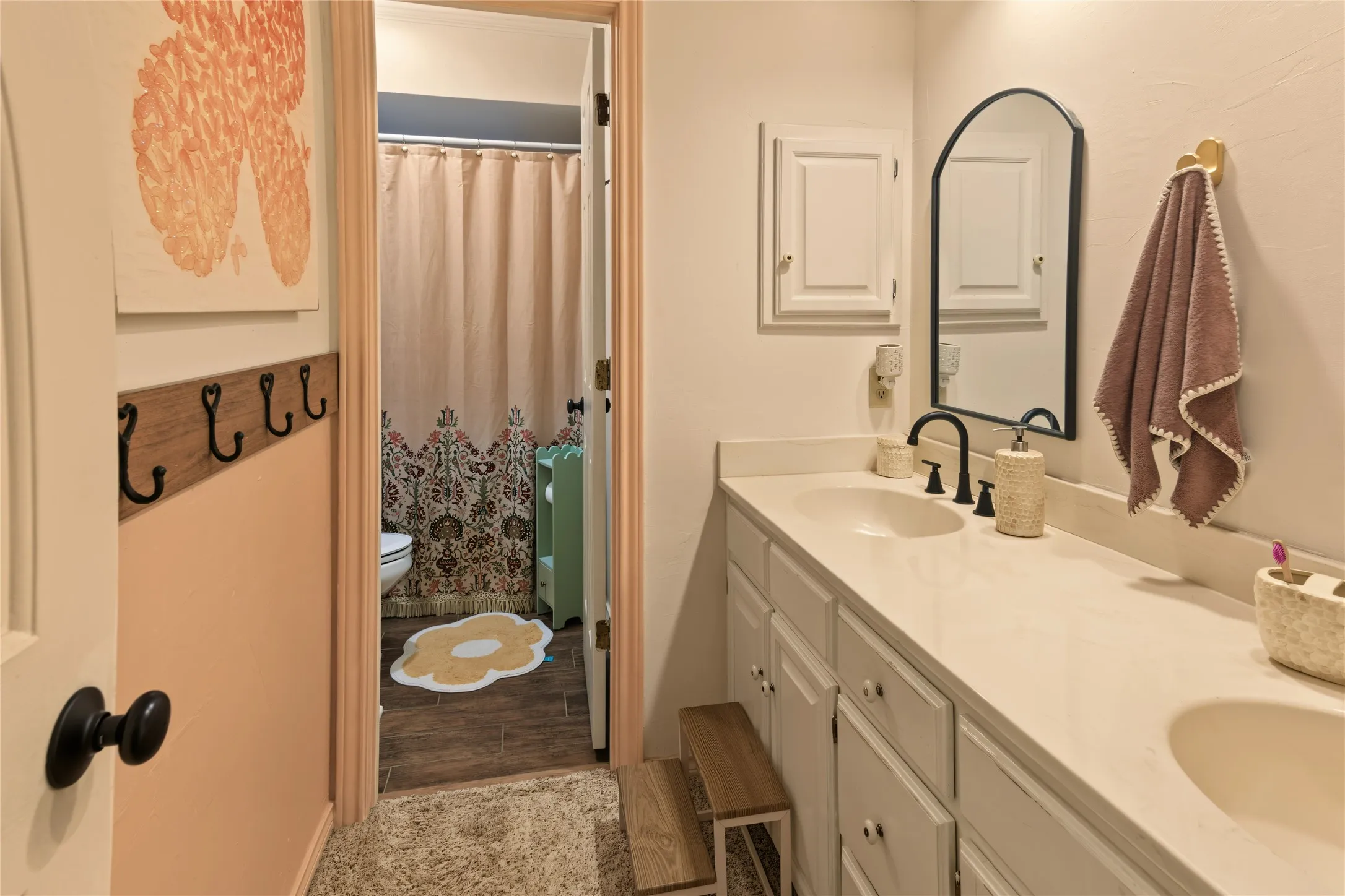 Dual vanity with integrated sinks, a black arched mirror, and black plumbing fixtures