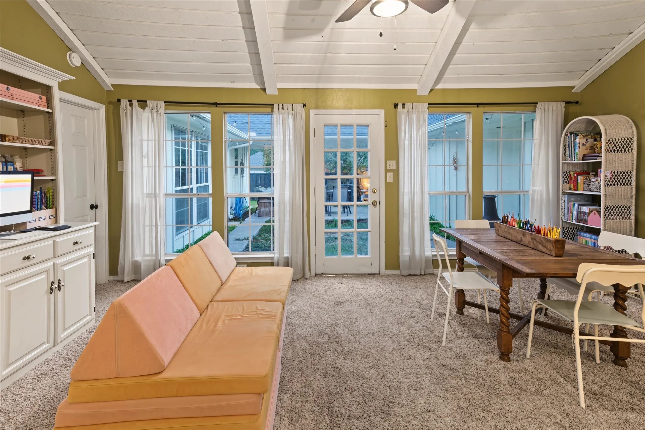 Expansive room featuring a vaulted ceiling with exposed white beams and a ceiling fan
