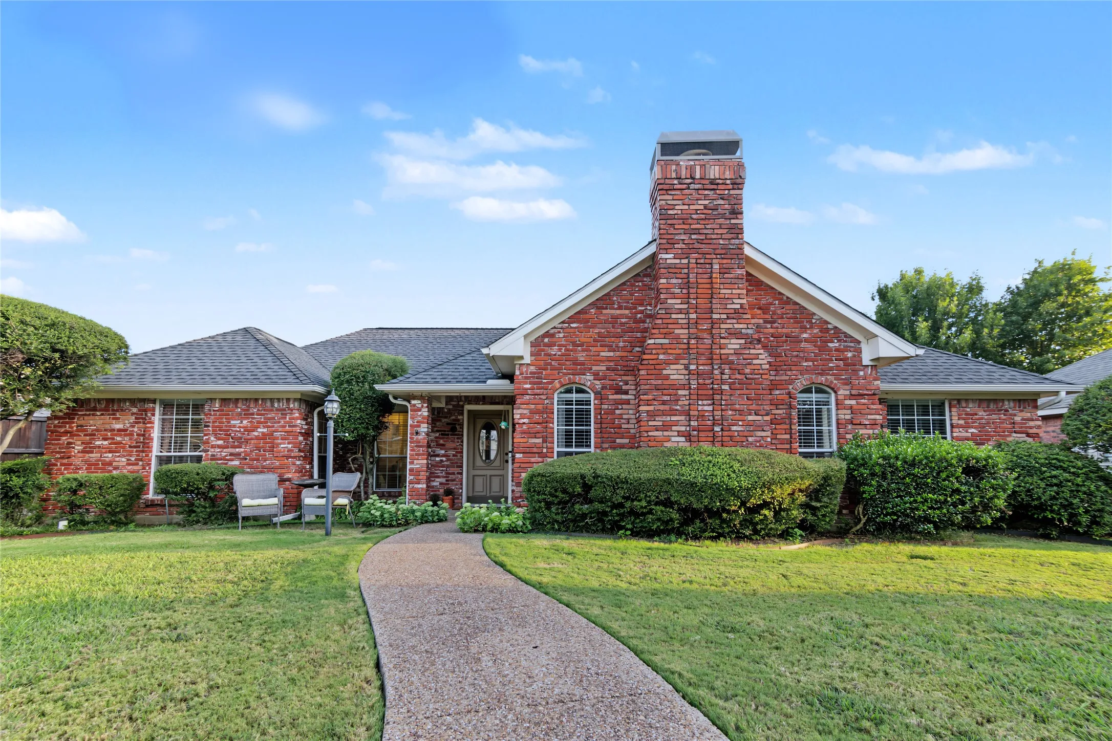 Brick exterior with a prominent brick chimney, arched windows, and a paved walkway