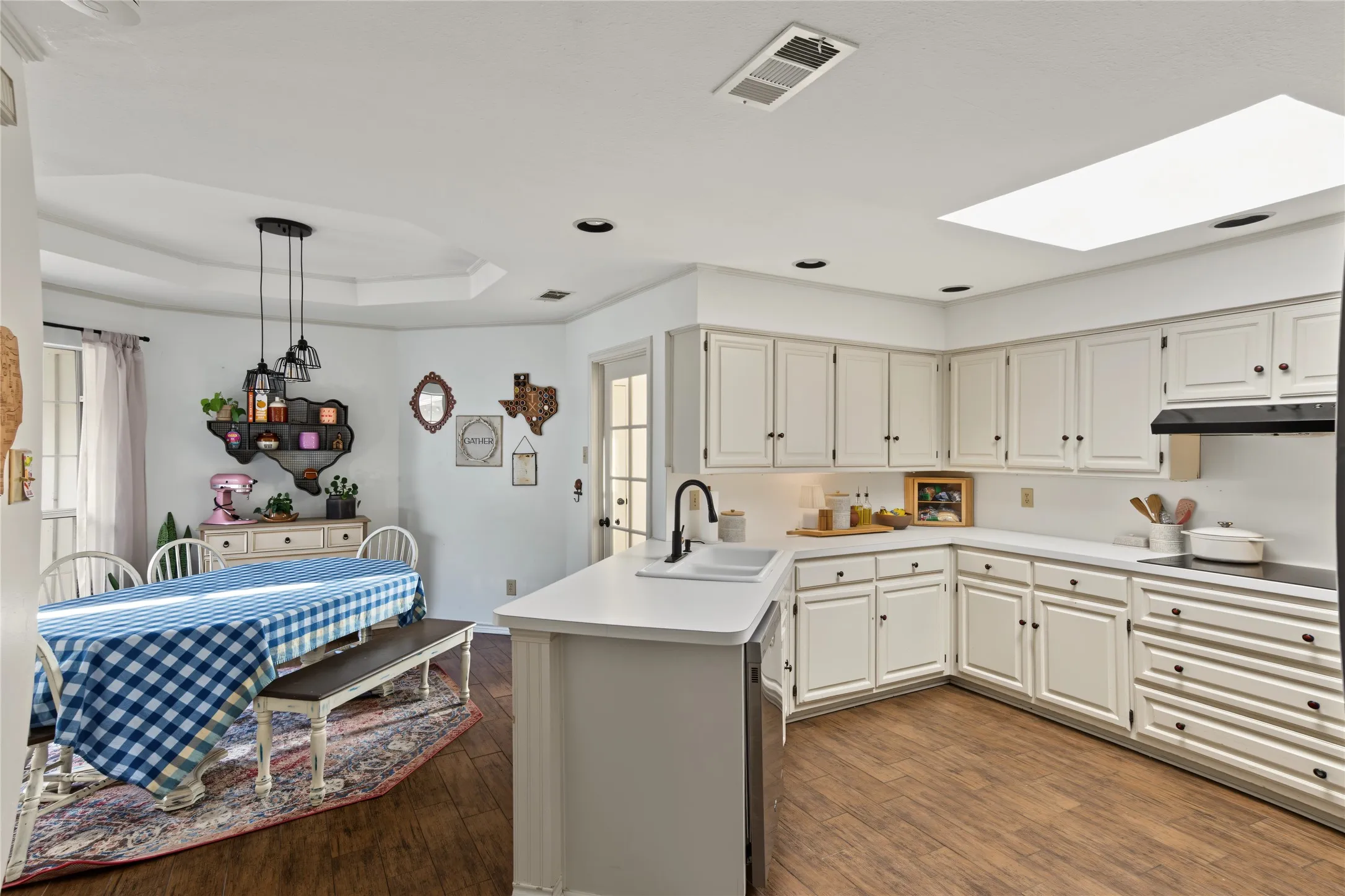 Kitchen featuring wood-finish flooring, white cabinetry, a skylight, and recessed lighting