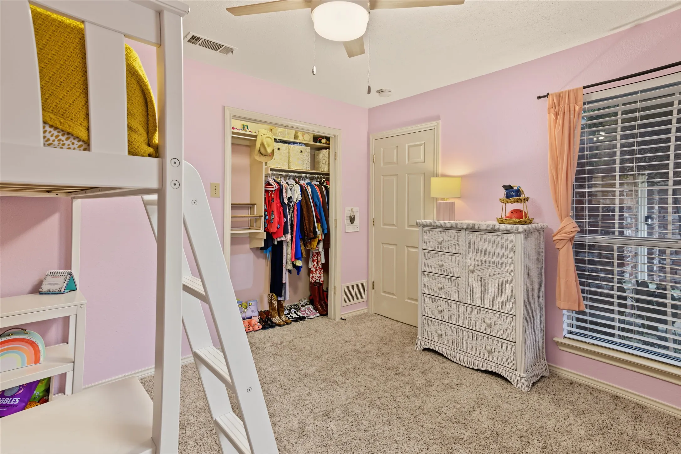 Carpeted bedroom with a built-in closet, ceiling fan, and a large window with blinds