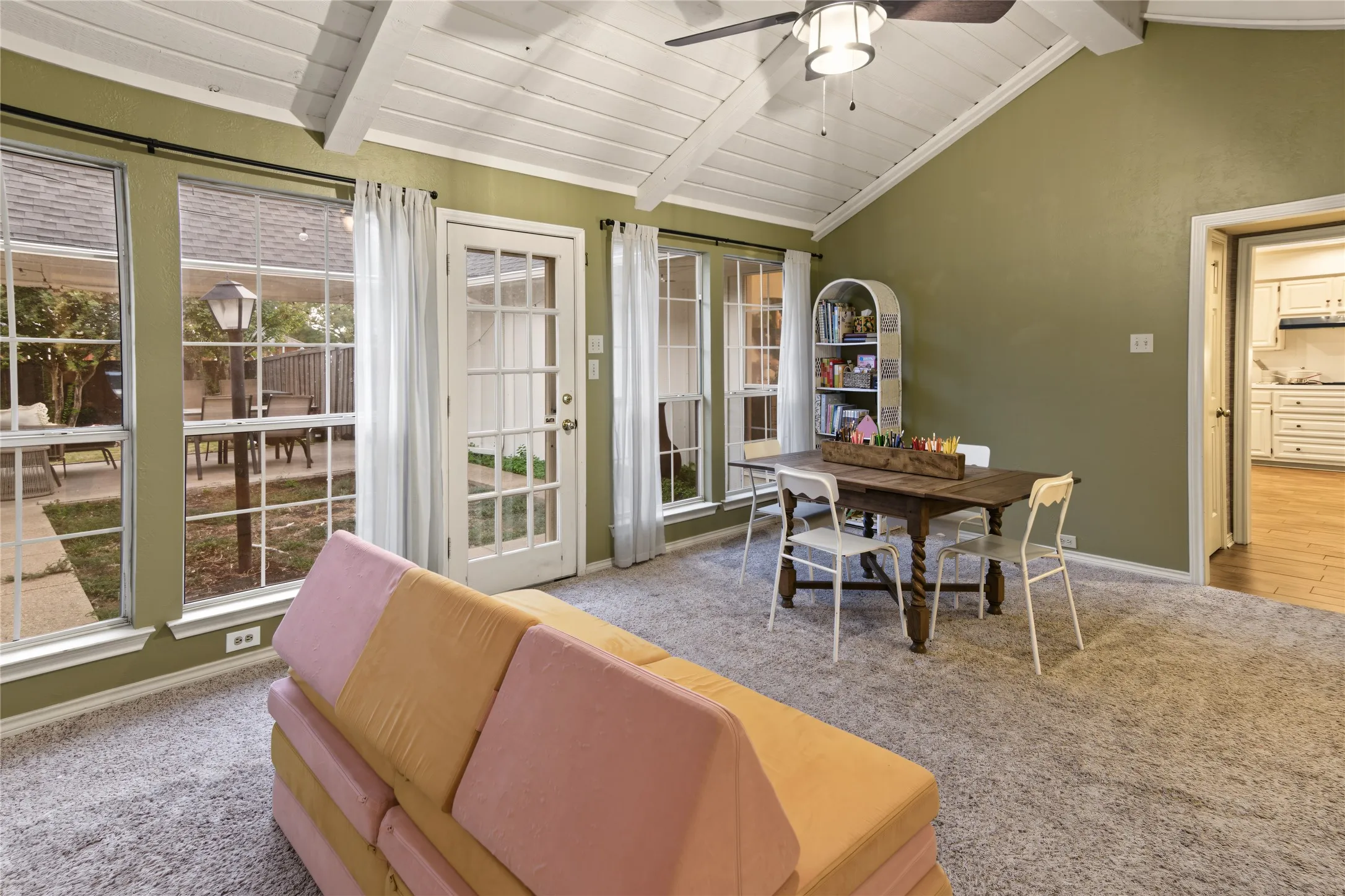 Vaulted ceiling with exposed beams, ceiling fan, and multiple windows