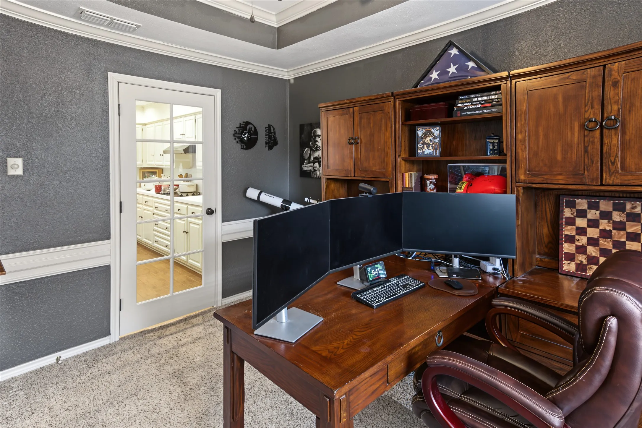 Room featuring built-in wood cabinetry, wood-finish desk, tray ceiling, and a French door with glass panels