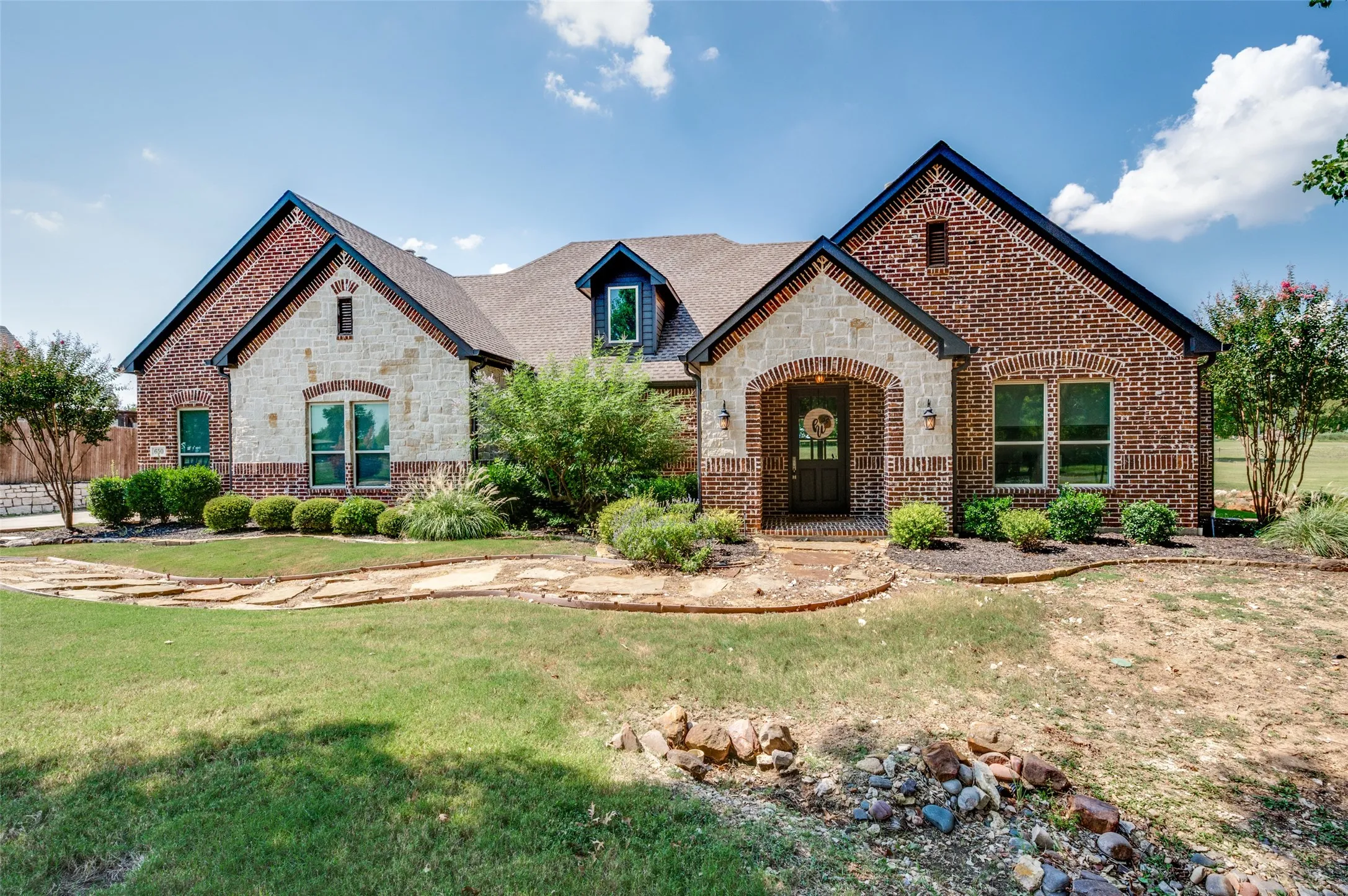 Brick and stone facade with arched entry, gabled rooflines, and dormer window