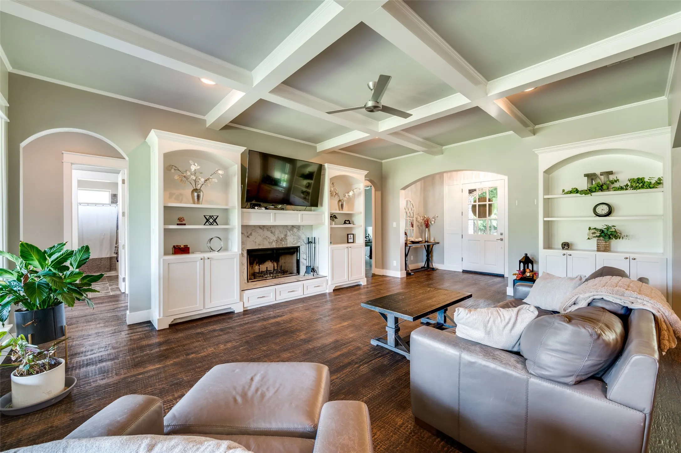 Coffered ceiling with a ceiling fan, recessed lighting, wood-finish flooring, built-in shelving, and an arched entryway