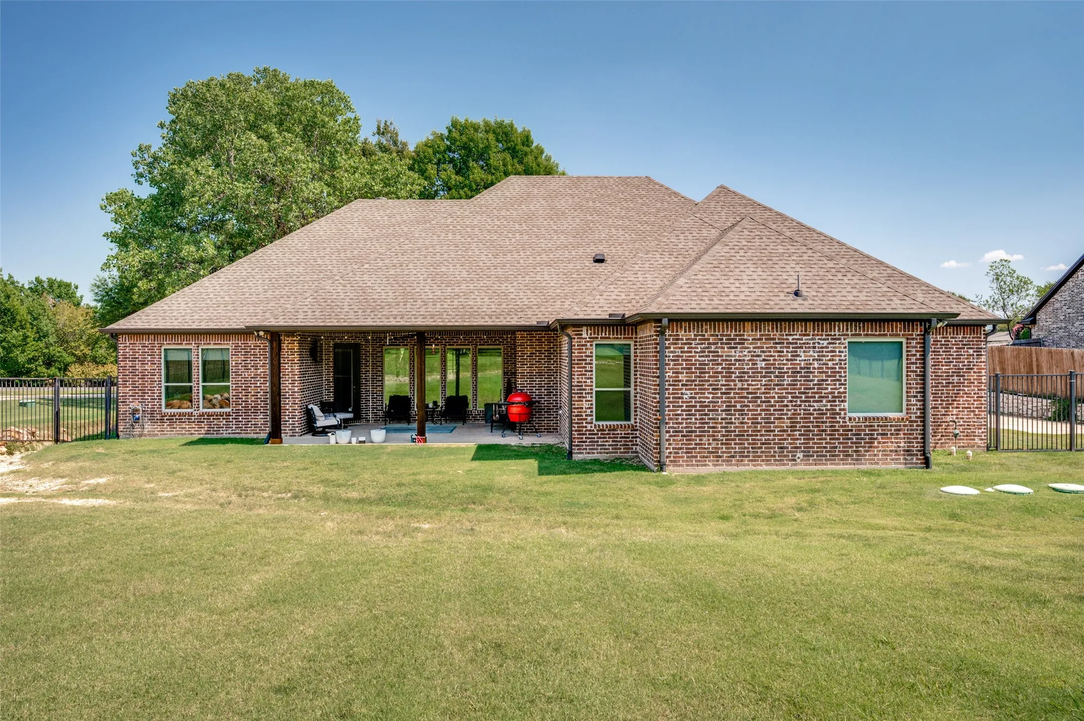 Expansive backyard featuring a brick exterior, covered patio, and perimeter fencing