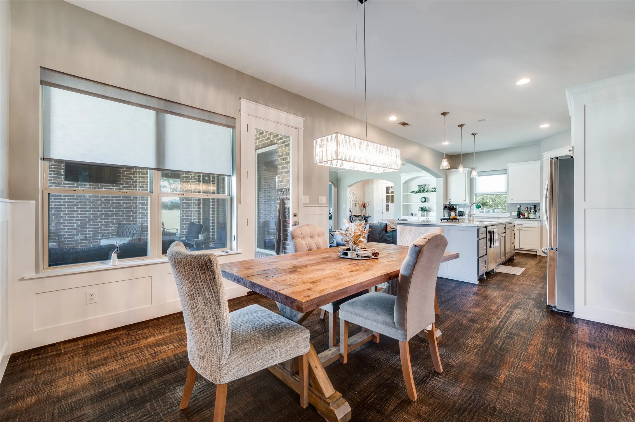 Dark wood-finish flooring, white wainscoting, and a crystal chandelier