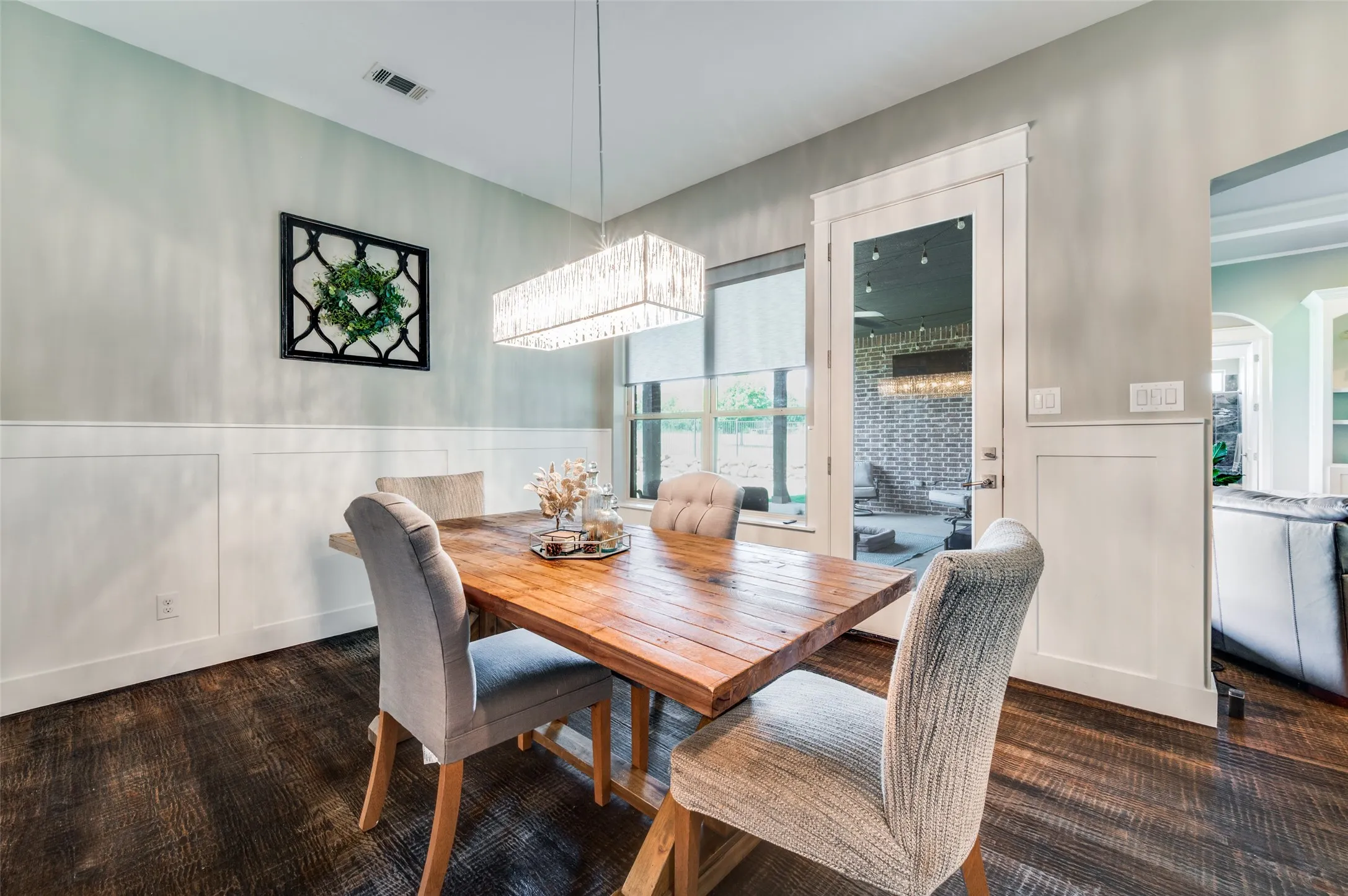 Wood-finish flooring with wainscoting and a contemporary rectangular chandelier
