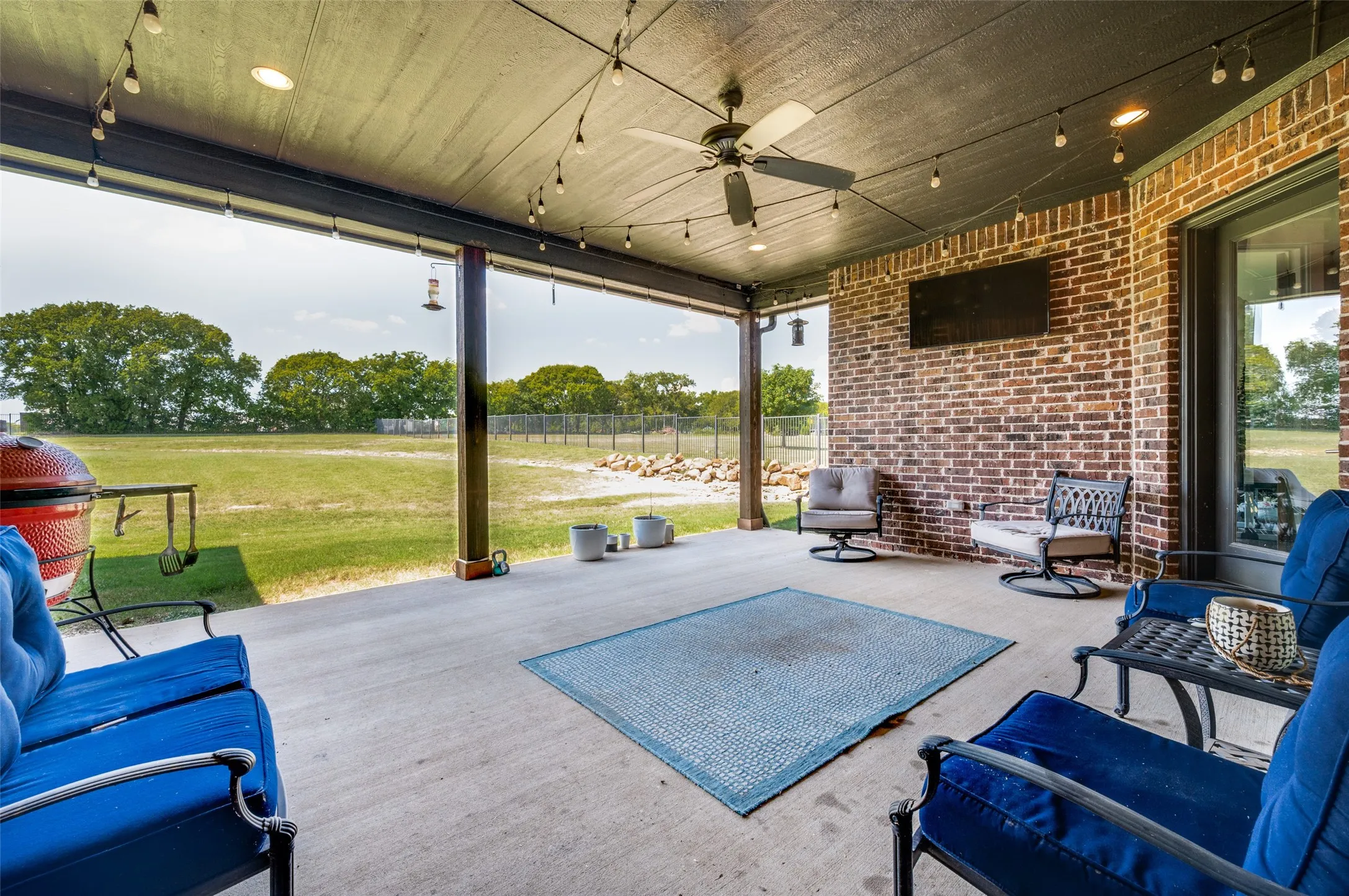 Expansive covered patio with concrete flooring, brick exterior wall, and ceiling fan