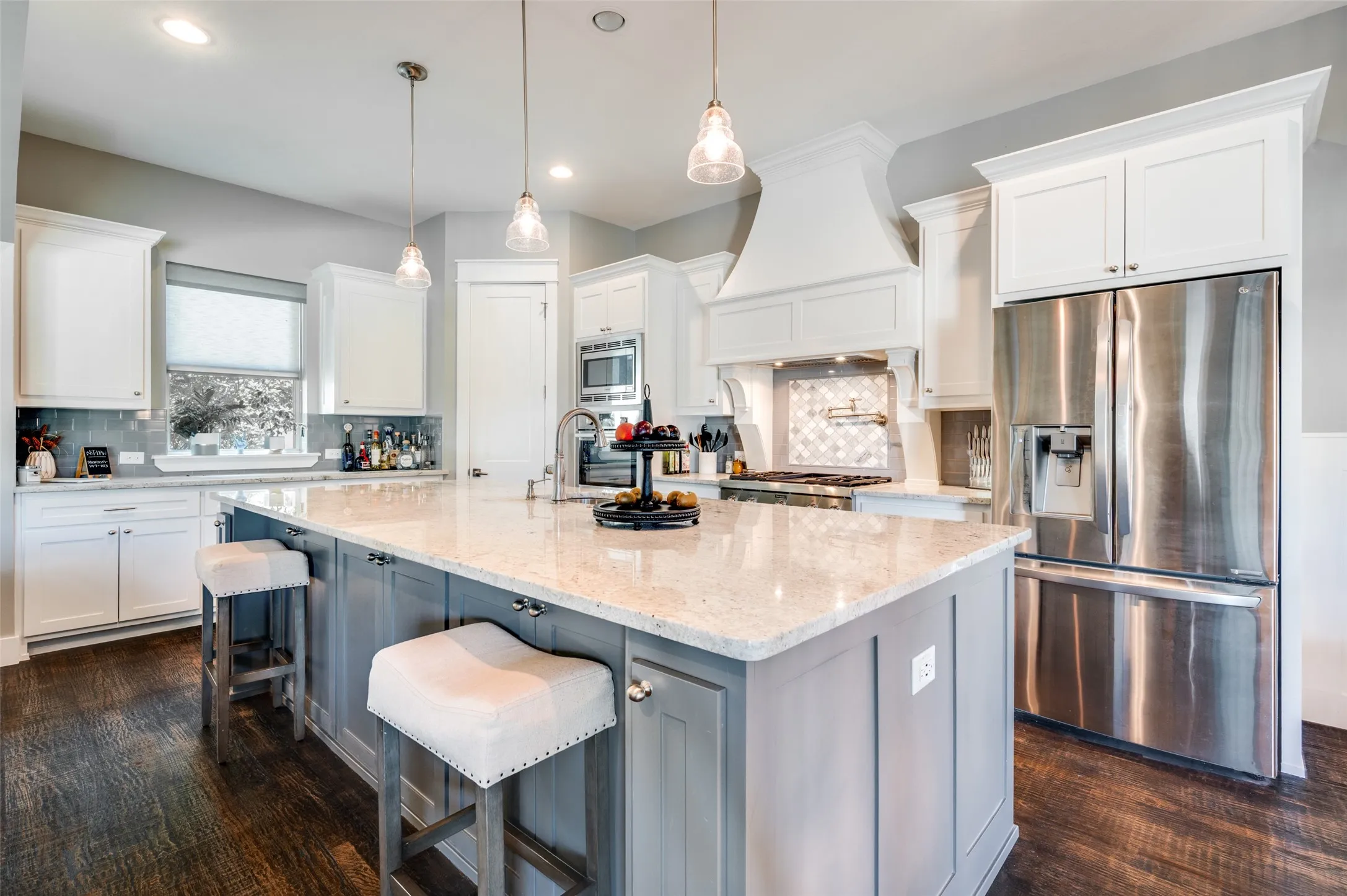 Spacious kitchen featuring a large island, stainless steel appliances, wood-finish flooring, white cabinetry, and recessed lighting